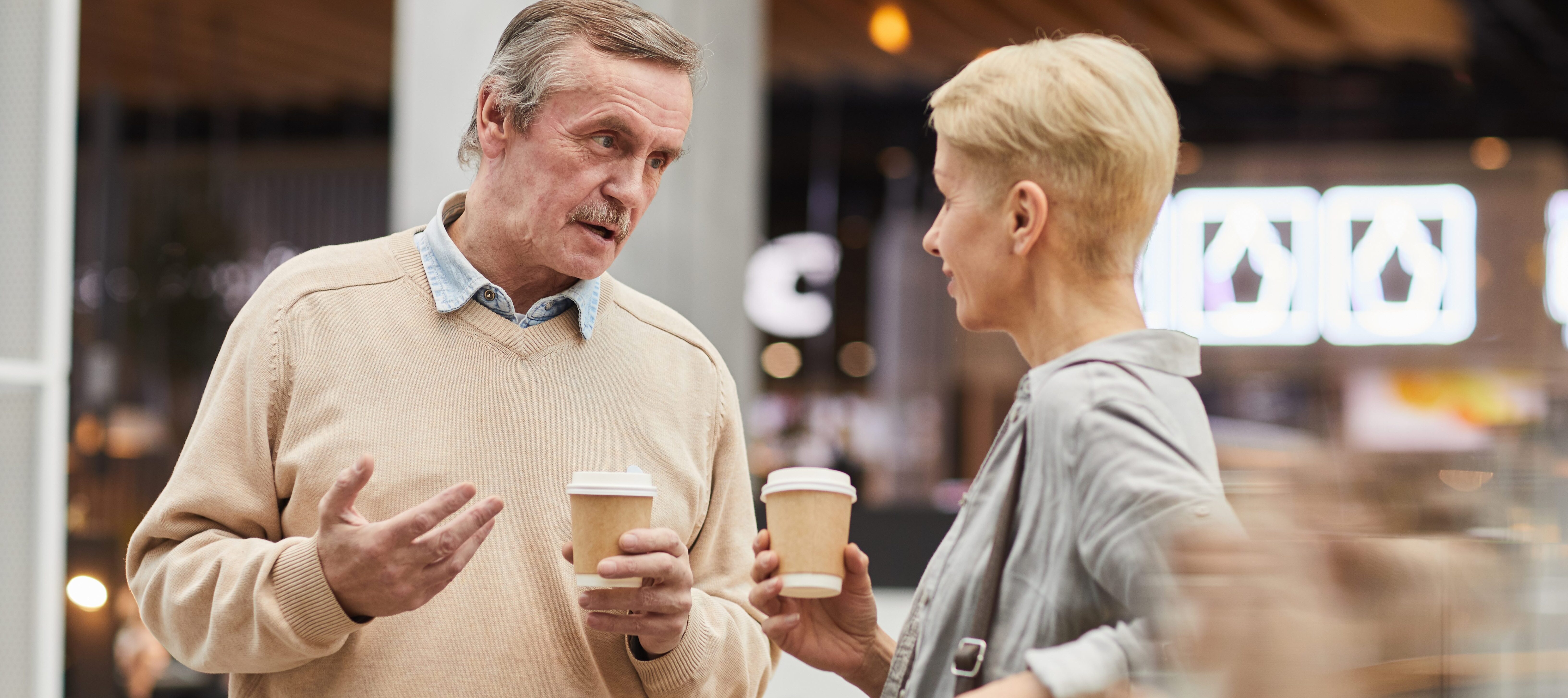 Retired couple chatting while drinking takeout coffee