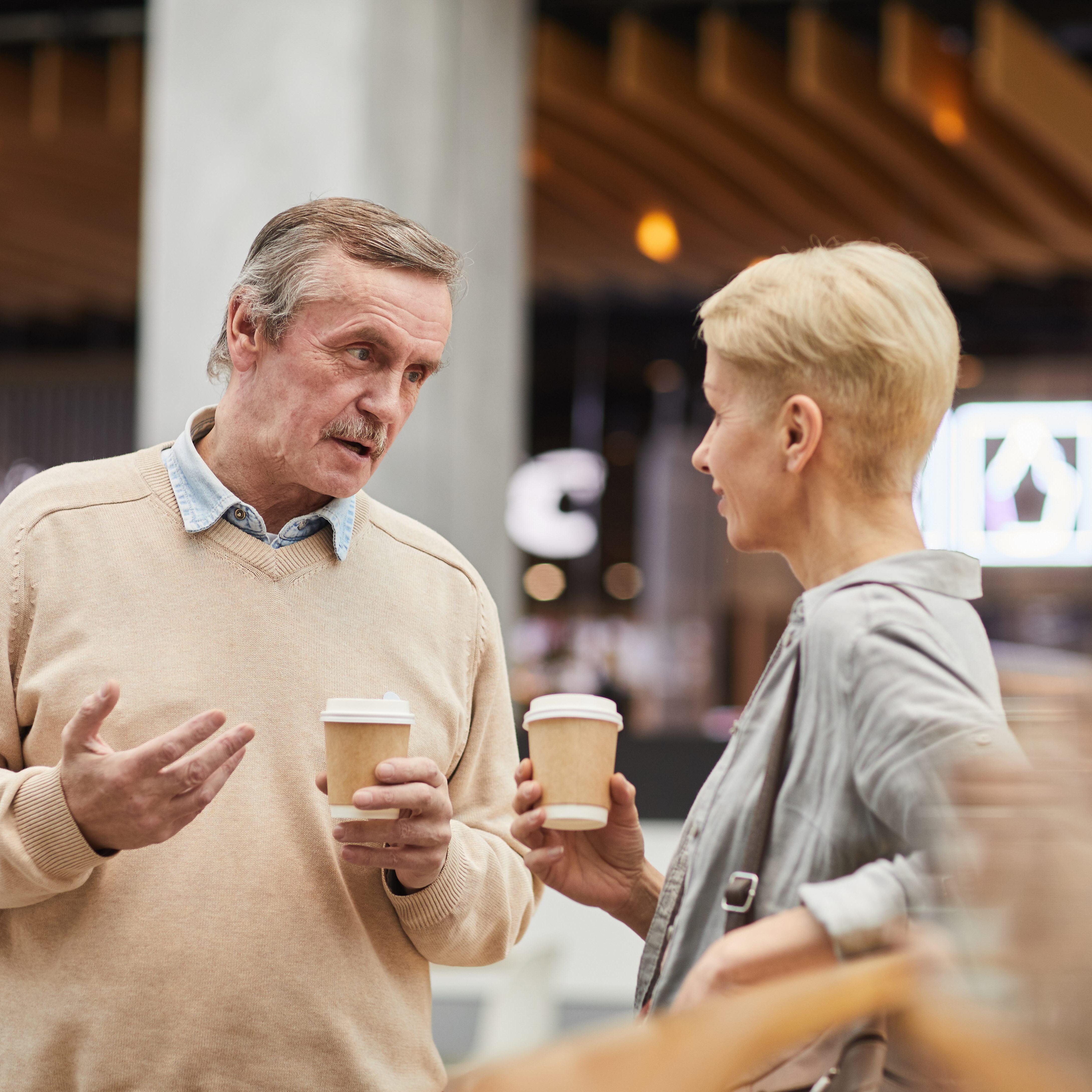 Retired couple chatting while drinking takeout coffee