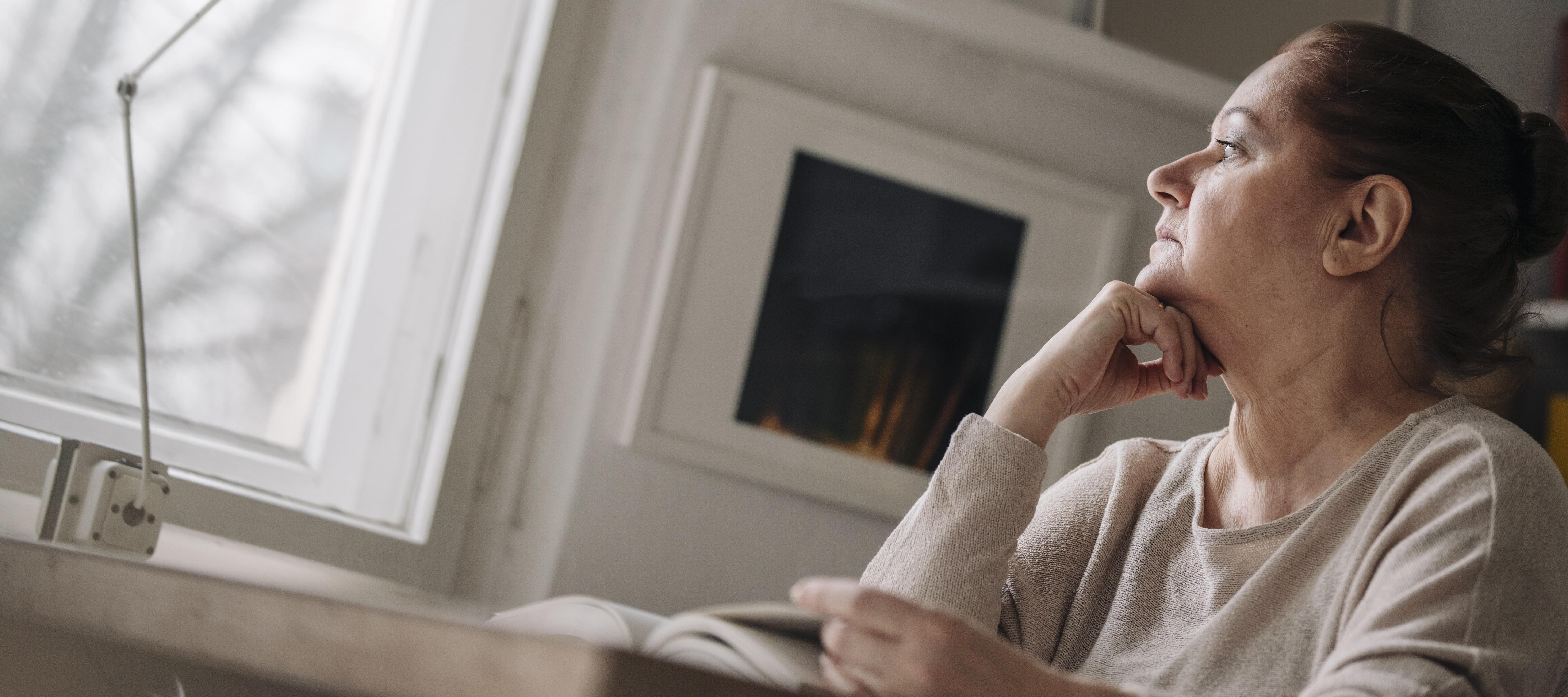 60 year old woman reading a book and pondering