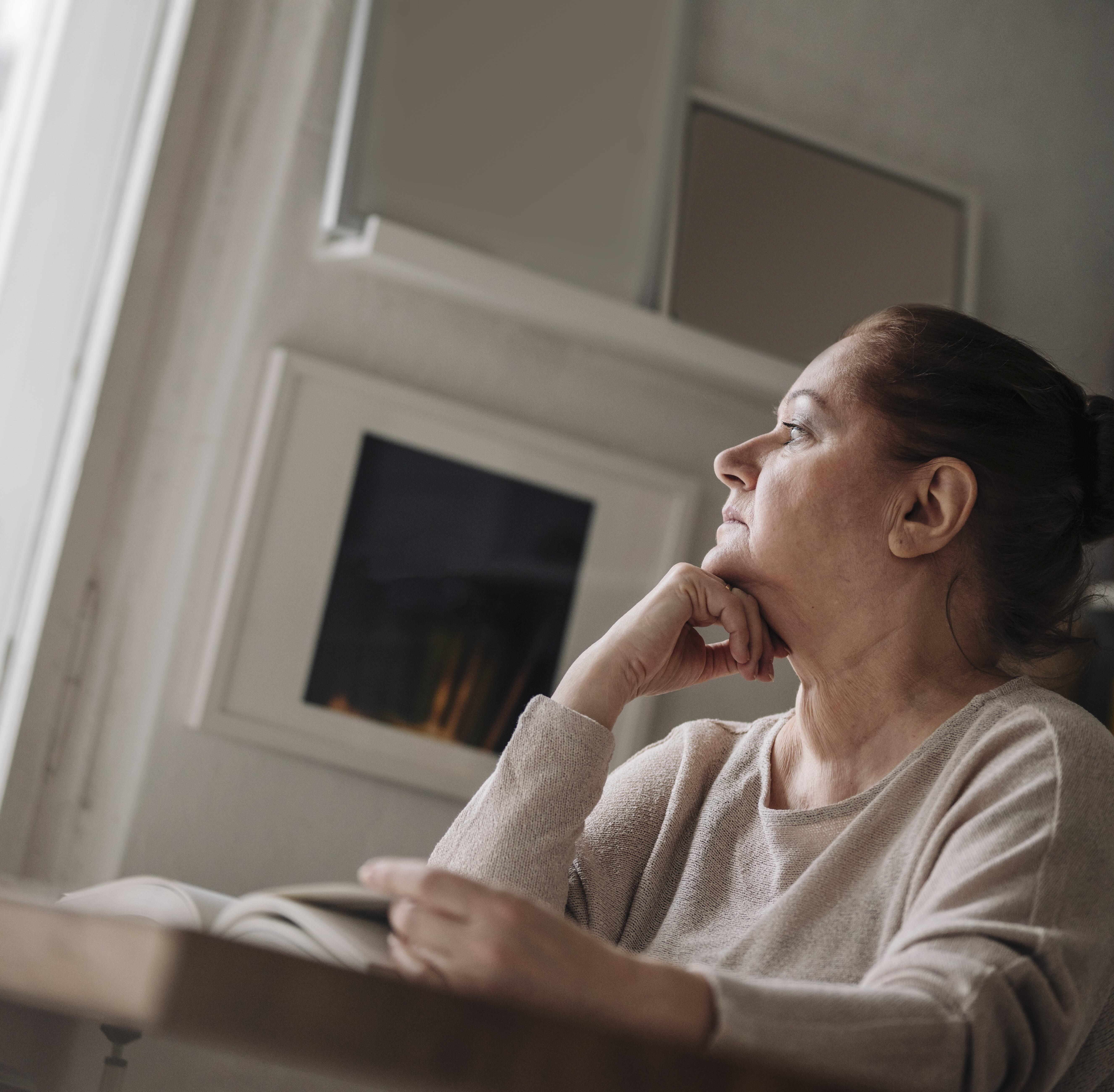 60 year old woman reading a book and pondering