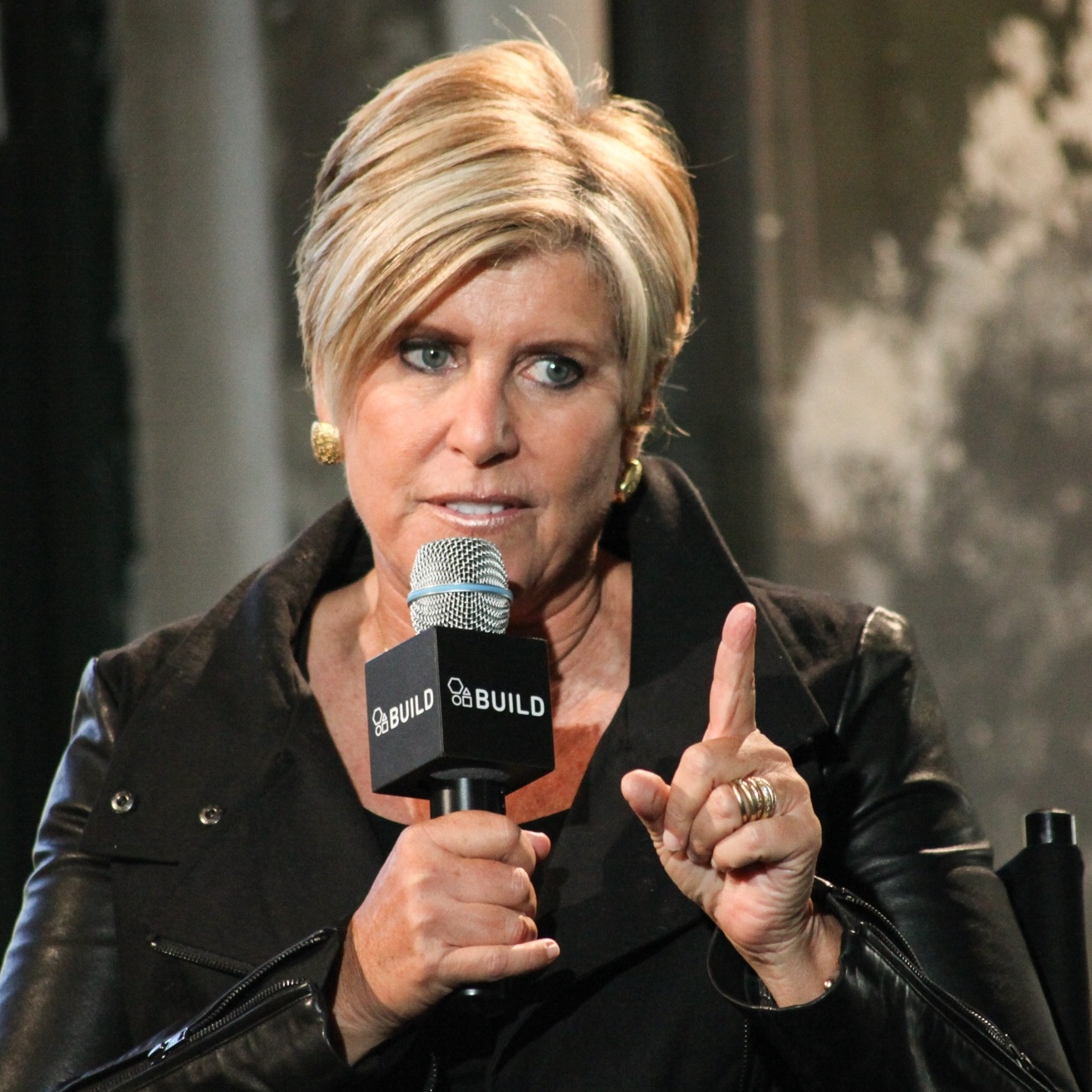 On the left Suze Orman speaks into a microphone, on the right Dave Ramsey answers a call on his show