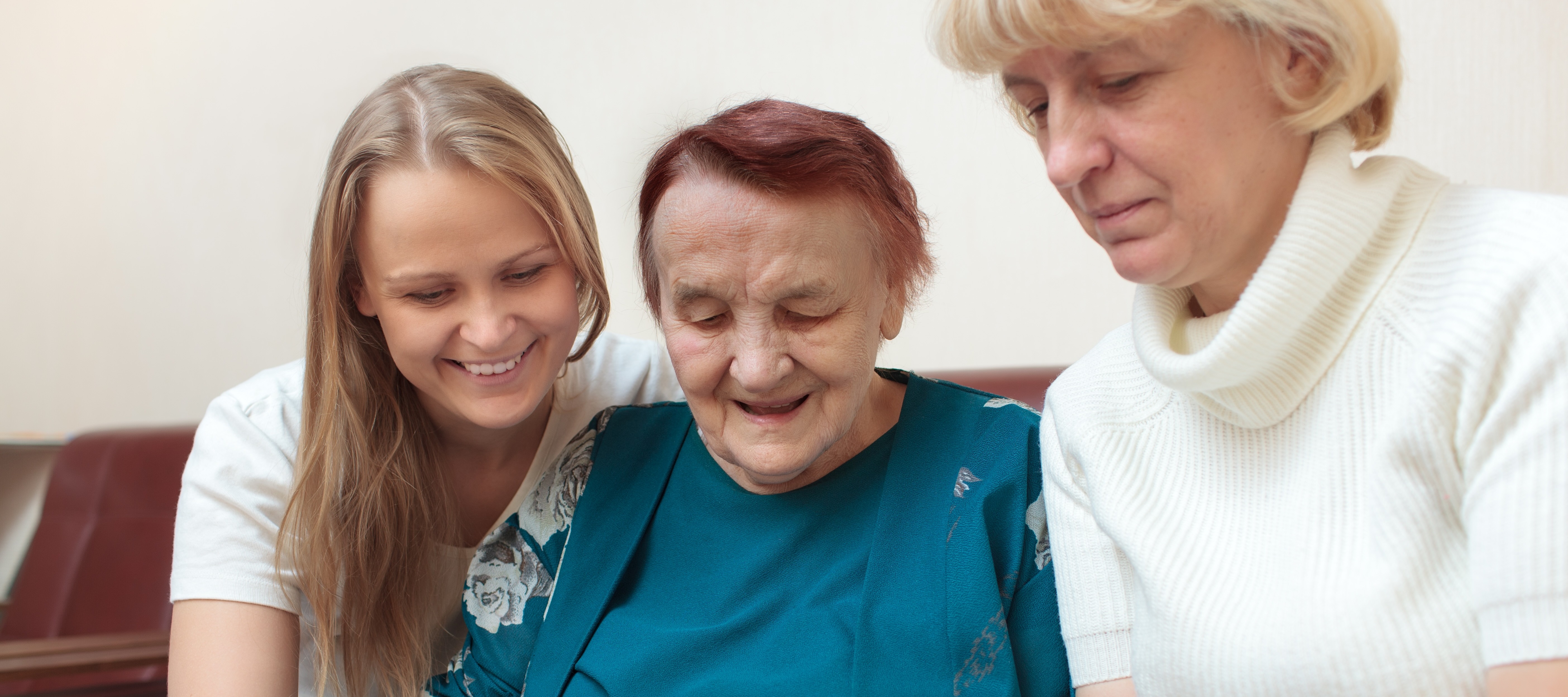 Teen sitting with her grandma and mother looking at old photos