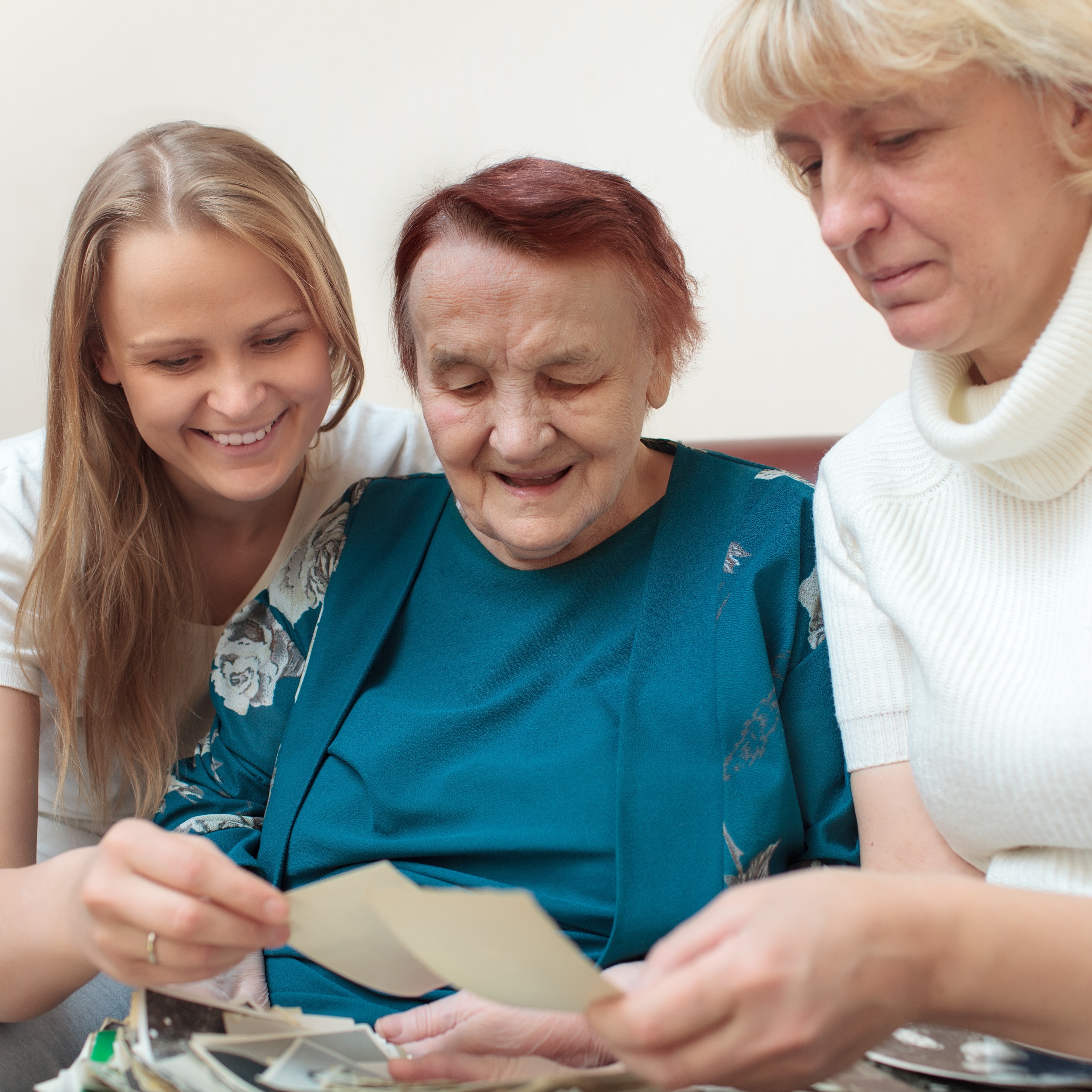 Teen sitting with her grandma and mother looking at old photos