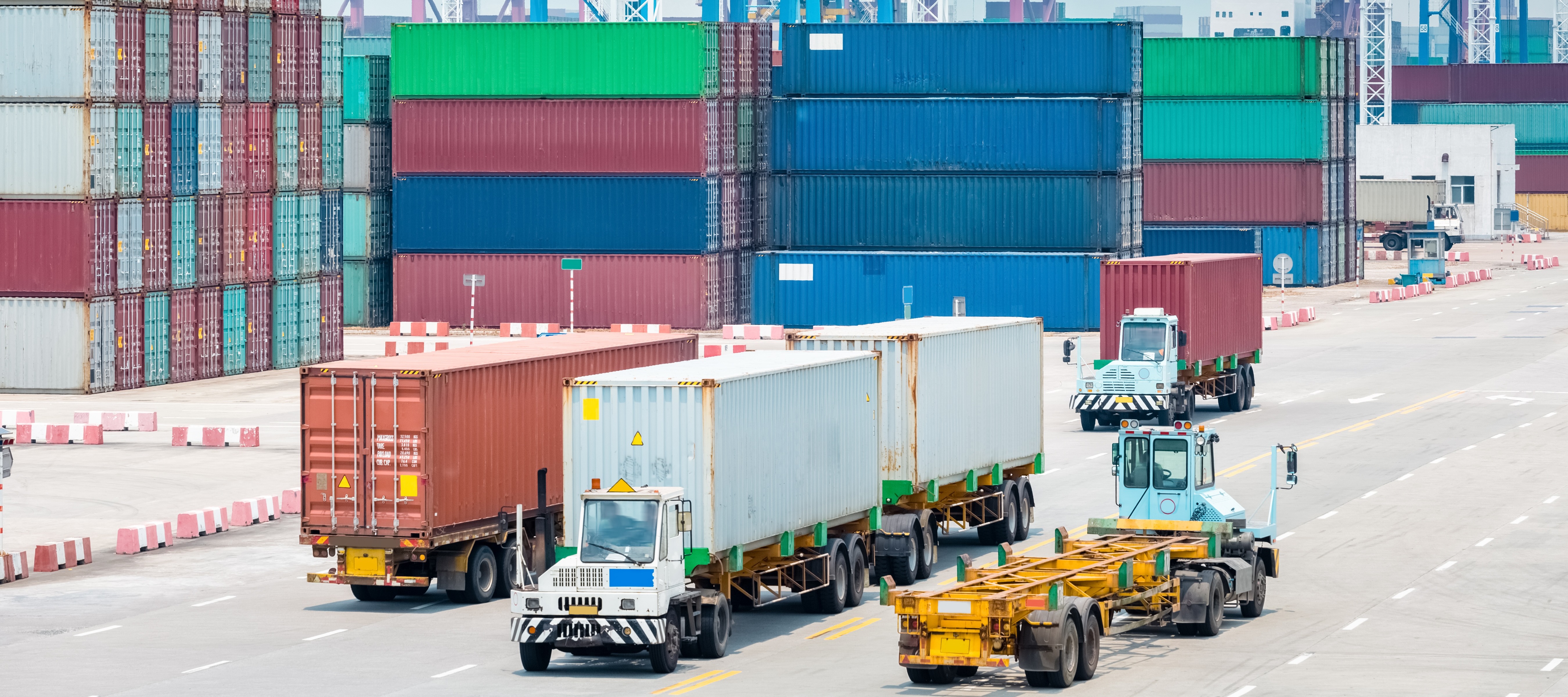 Shipping containers at a shipping port with trucks driving alongside them