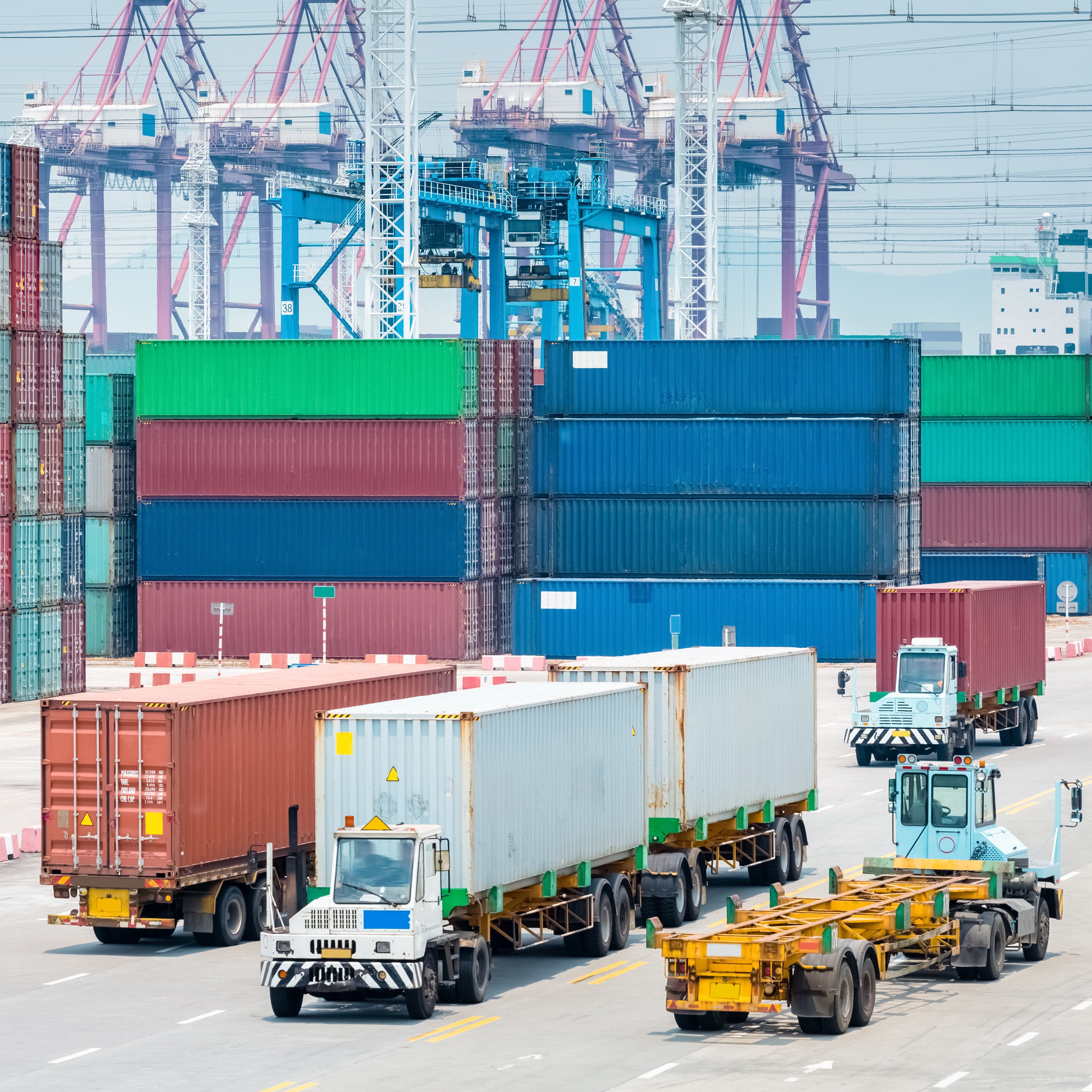 Shipping containers at a shipping port with trucks driving alongside them
