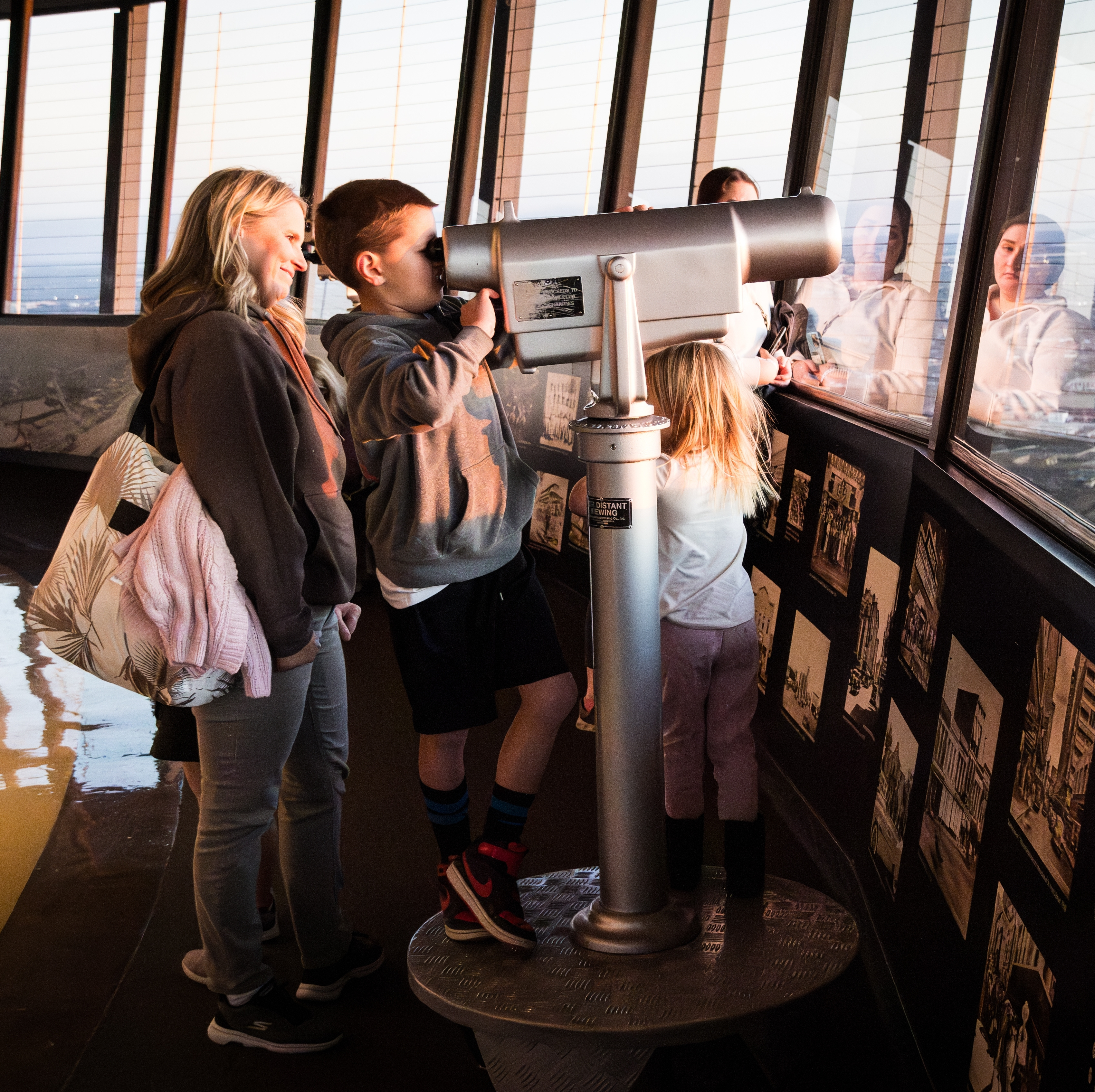 A mother and her children take in the sights from the observation deck of a local building.