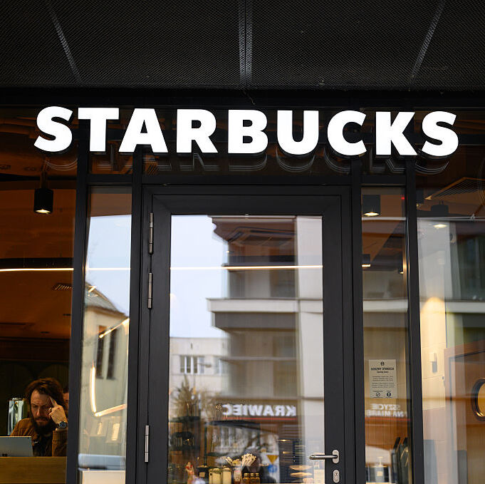 A photo of the Starbucks logo with a man working on a laptop