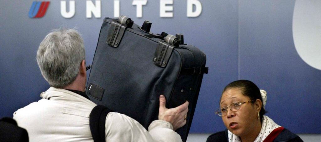 A photo of a United Airlines passenger checking in for their flight, showing the United Airlines airport staff their luggage
