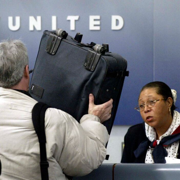 A photo of a United Airlines passenger checking in for their flight, showing the United Airlines airport staff their luggage