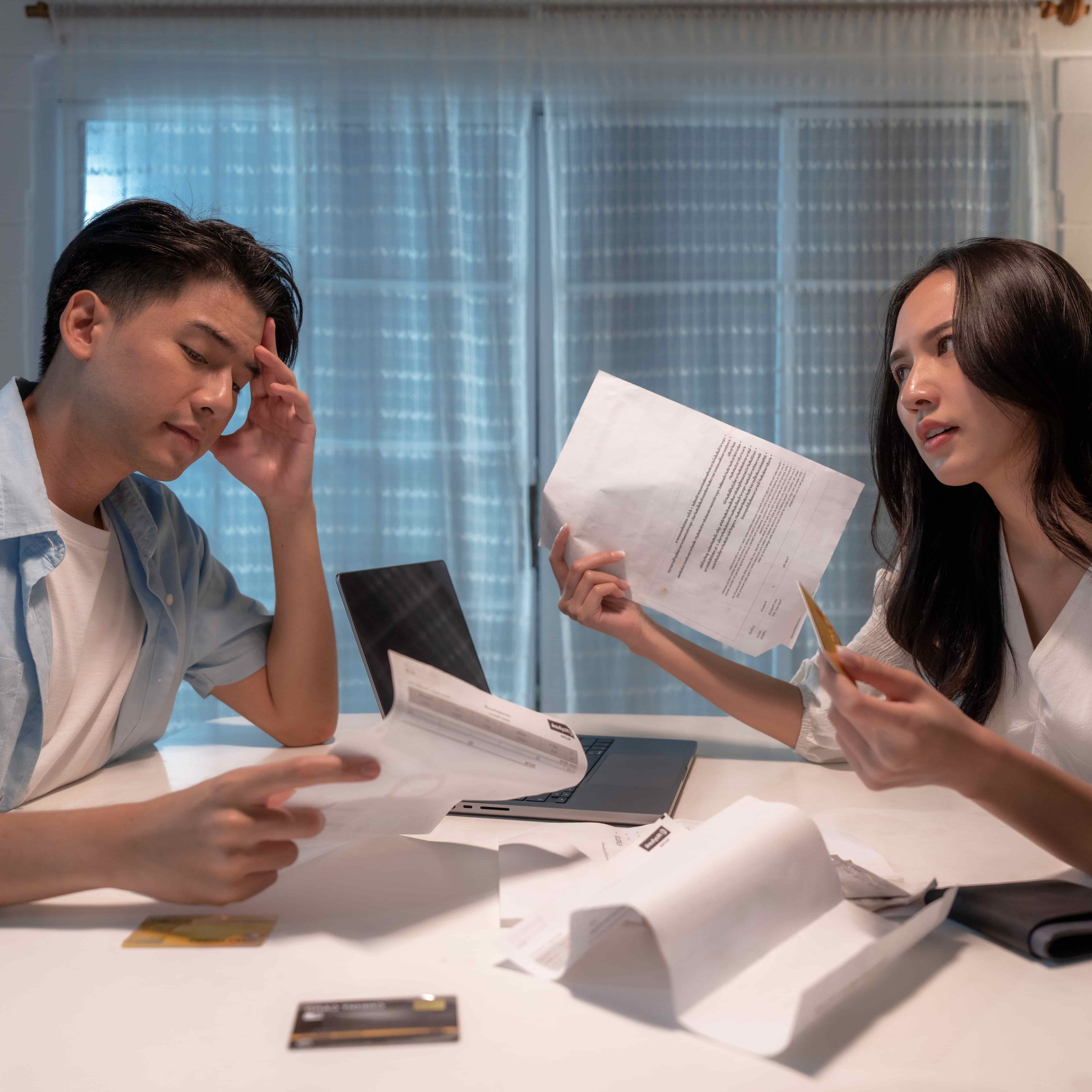 A photo of a visibly stressed man and a frustrated woman reviewing their finances together.