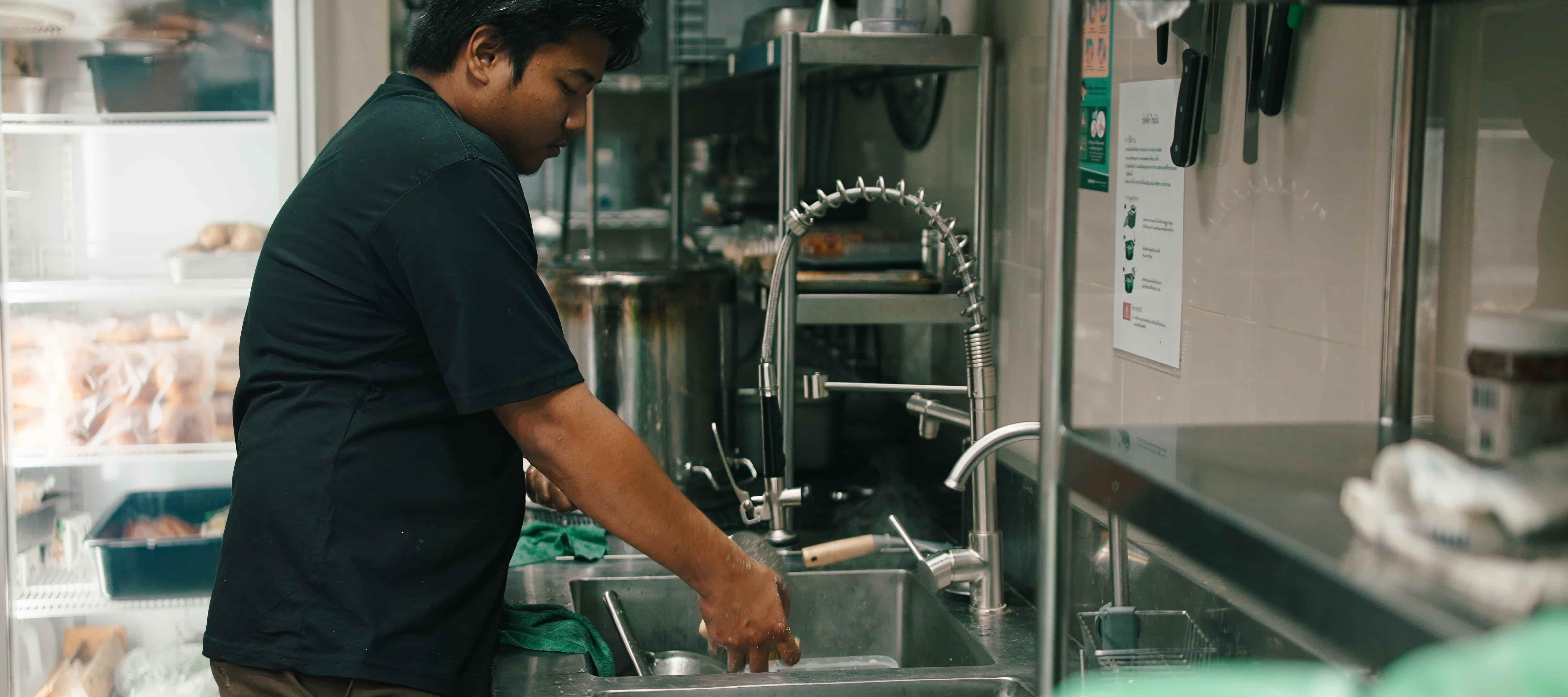 A photo of a restaurant worker washing dishes