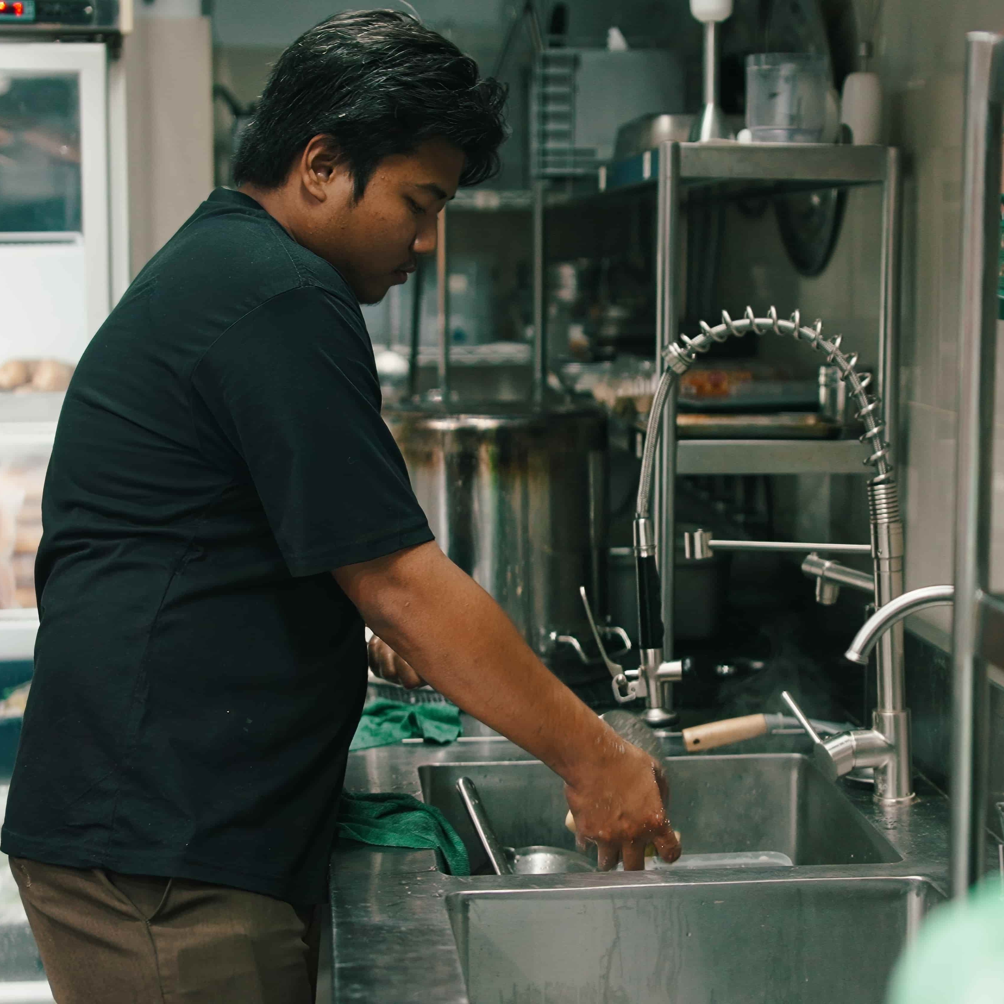 A photo of a restaurant worker washing dishes