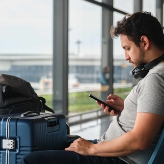 Man sitting at the airport with his luggage