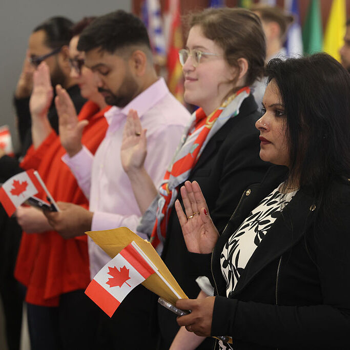 A photo of several people holding Canadian flags at a Canadian Citizenship Ceremony