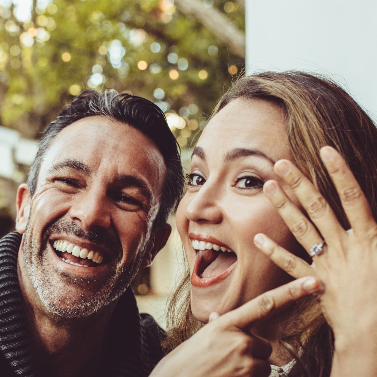 A couple show off a new engagement ring.