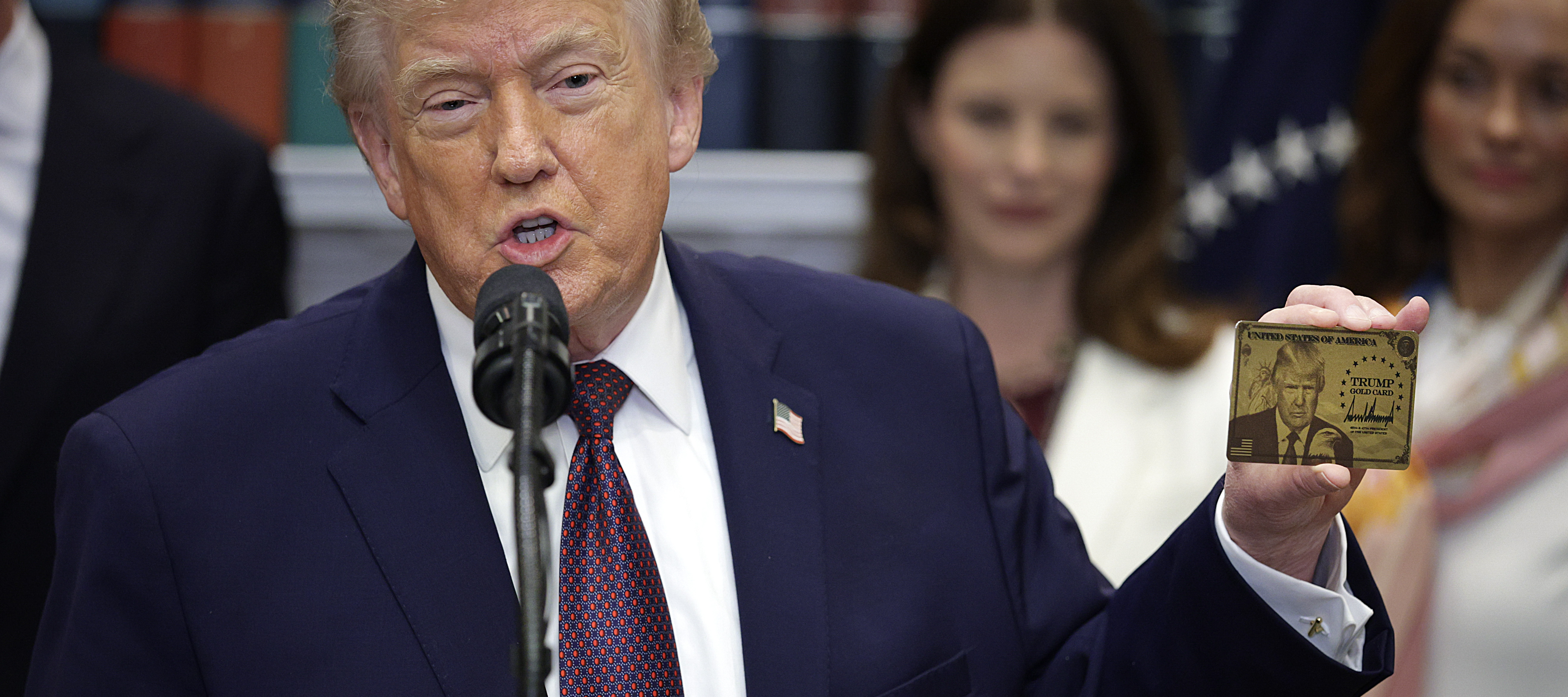 President Donald Trump holds up the Trump Gold Card.