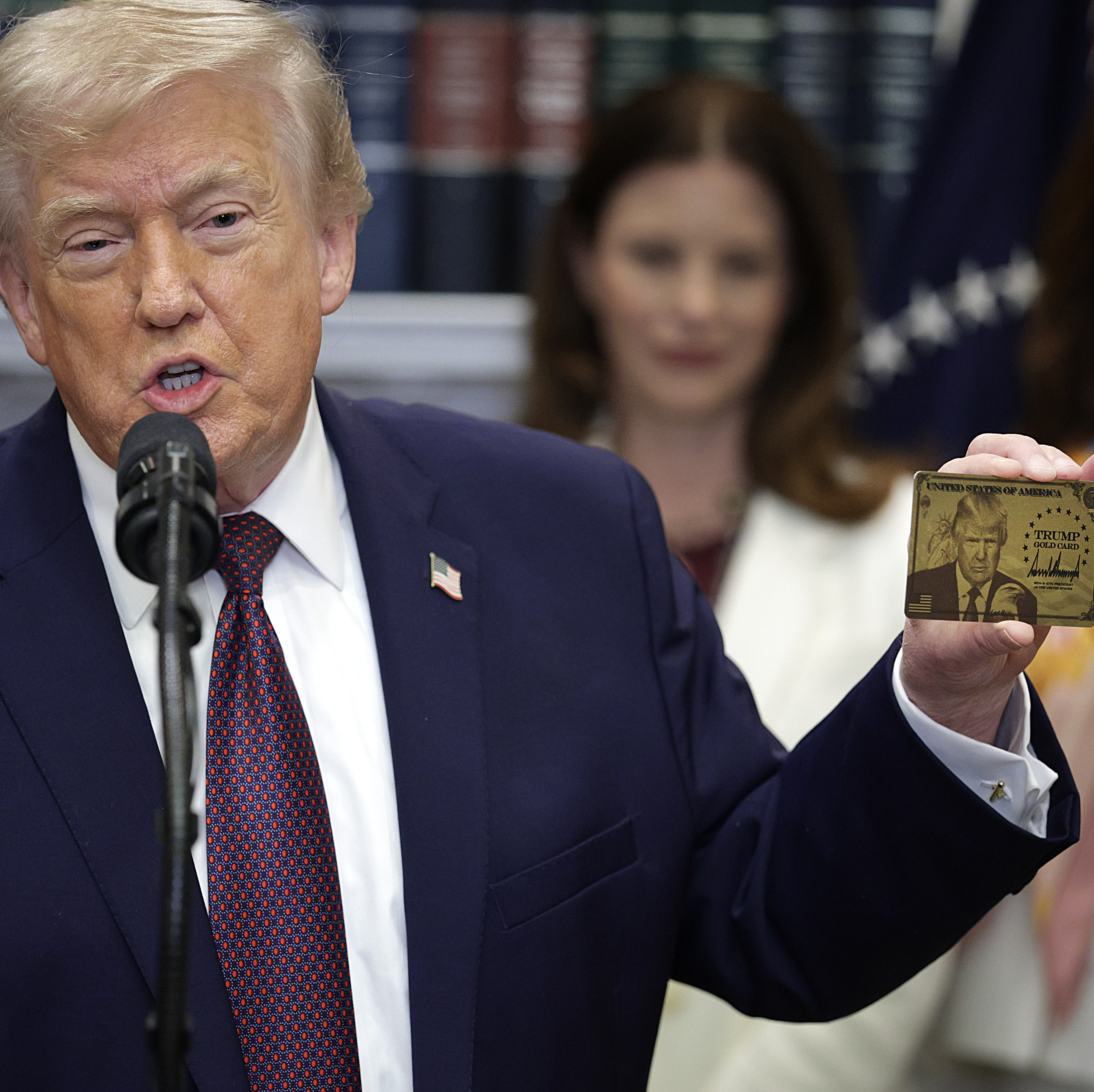 President Donald Trump holds up the Trump Gold Card.