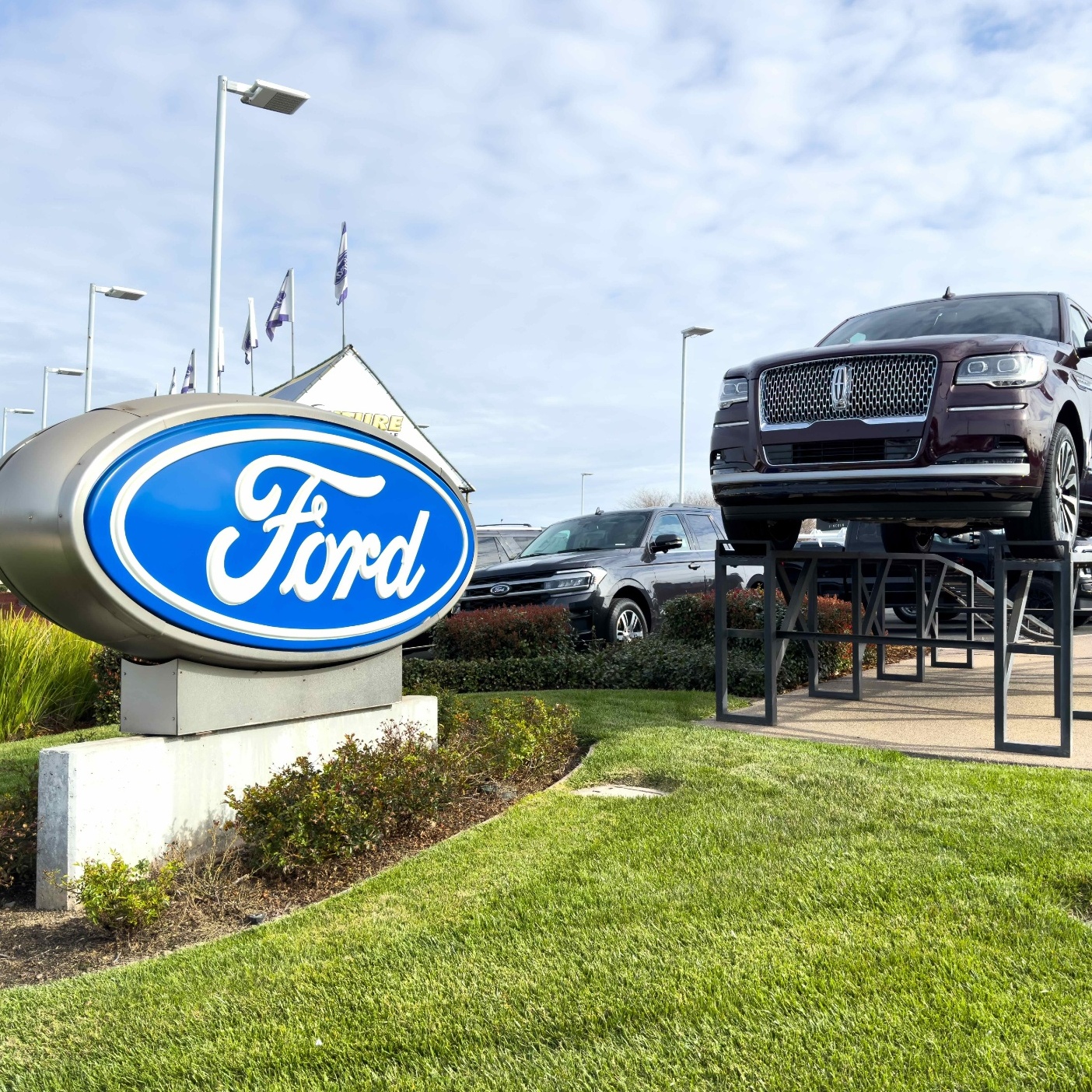 On the left is a hand holding a surveillance camera, on the right is a Ford dealership