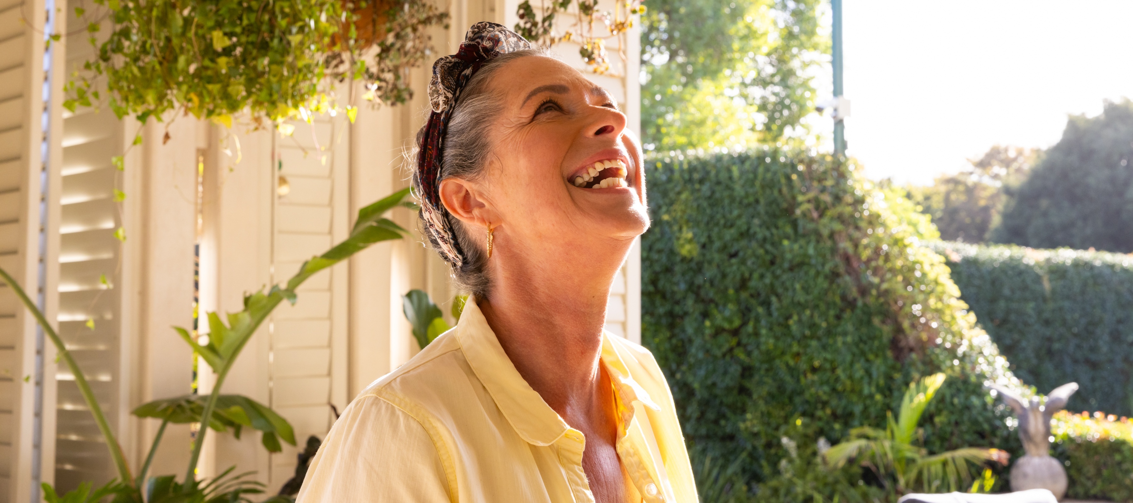 A woman is filled with joy on a beautiful day on her front porch.