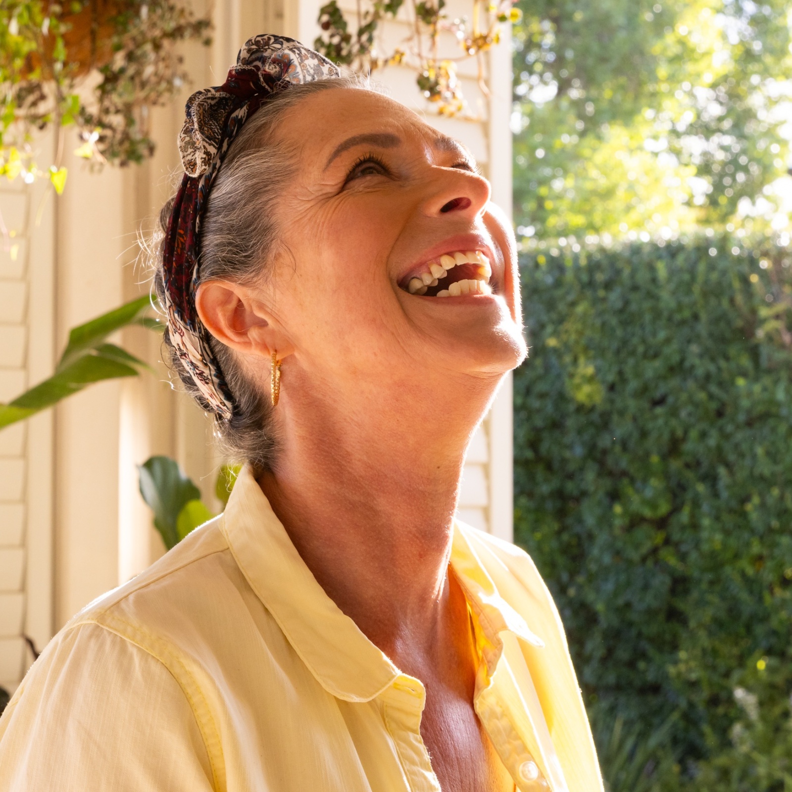 A woman is filled with joy on a beautiful day on her front porch.