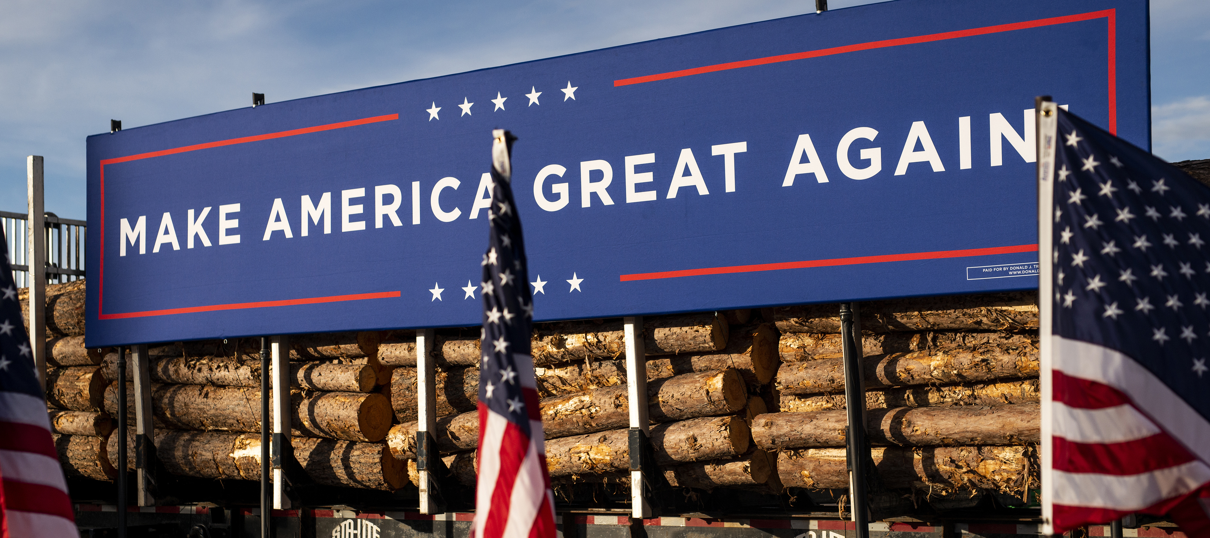 A logging truck features a large "Make America Great Again" banner on it.