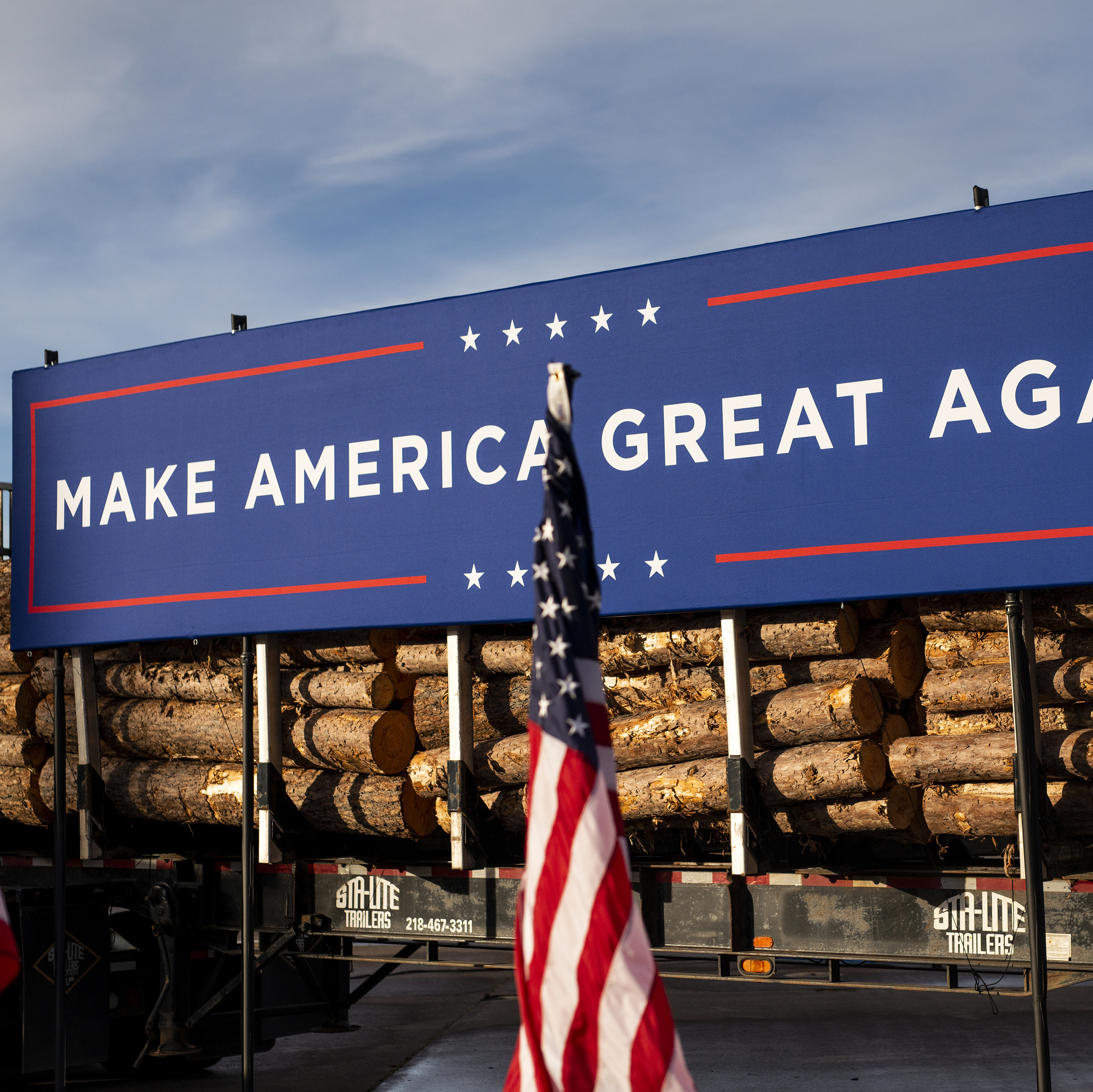 A logging truck features a large "Make America Great Again" banner on it.