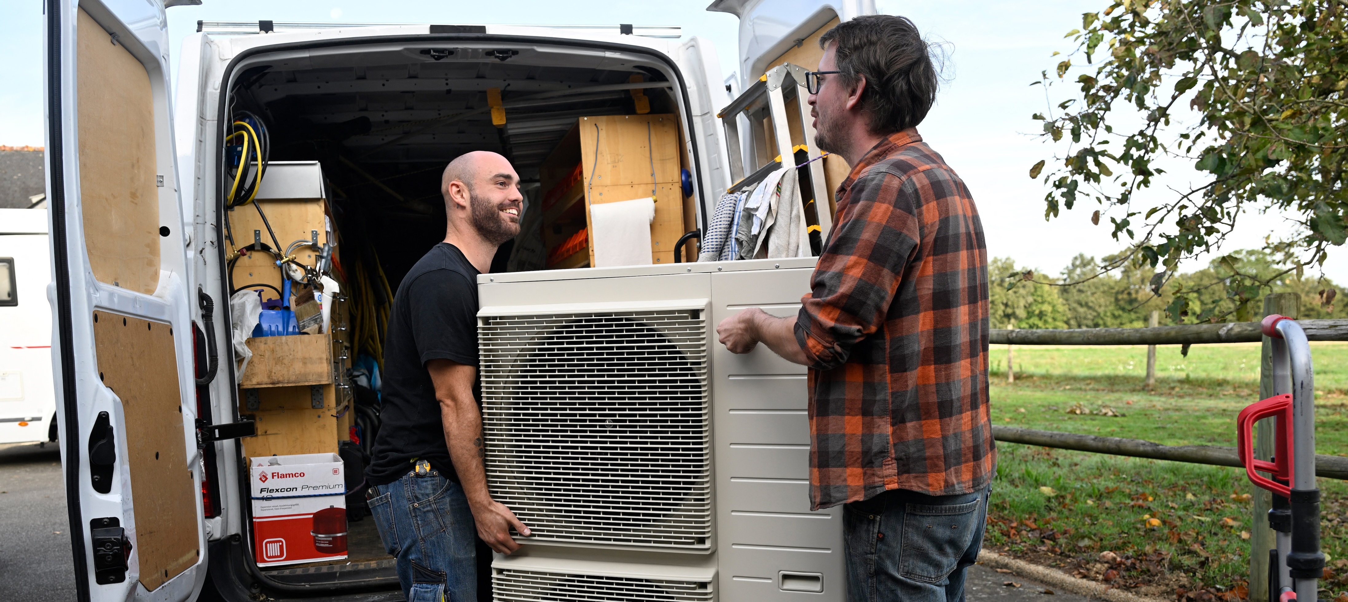 Workers carry a heat pump before installing it in a private home.
