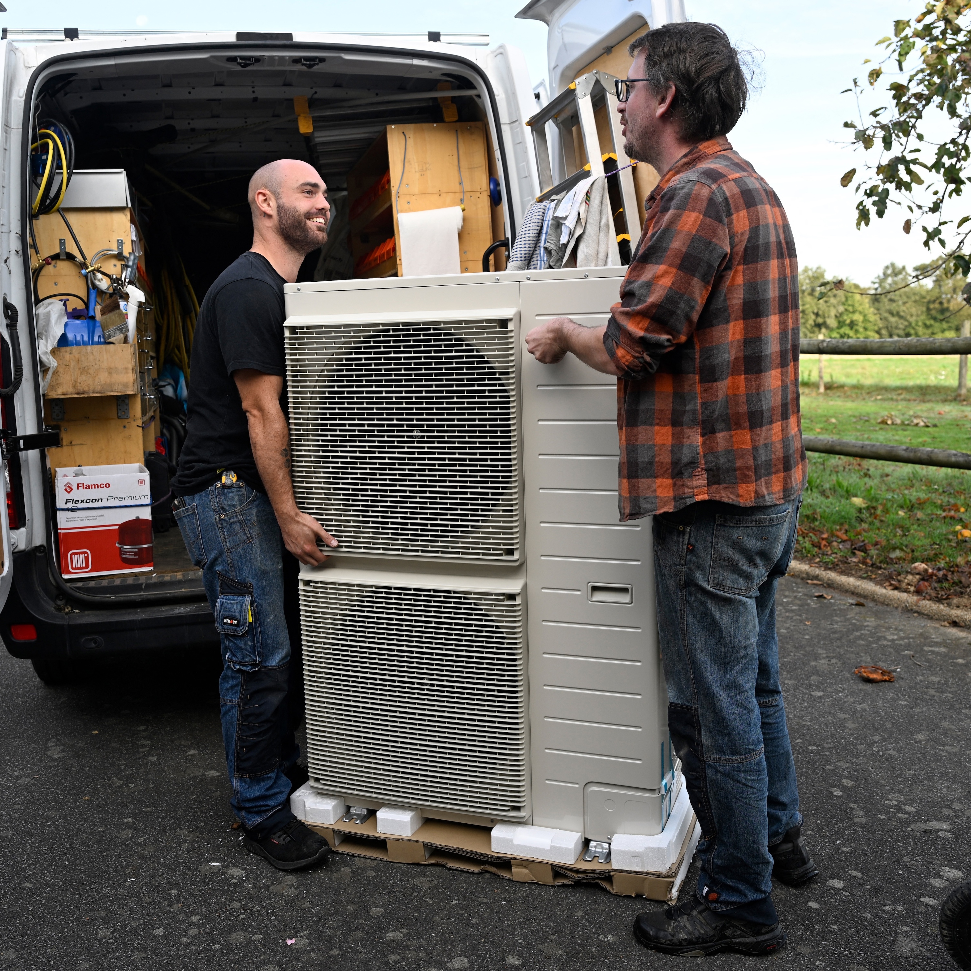 Workers carry a heat pump before installing it in a private home.