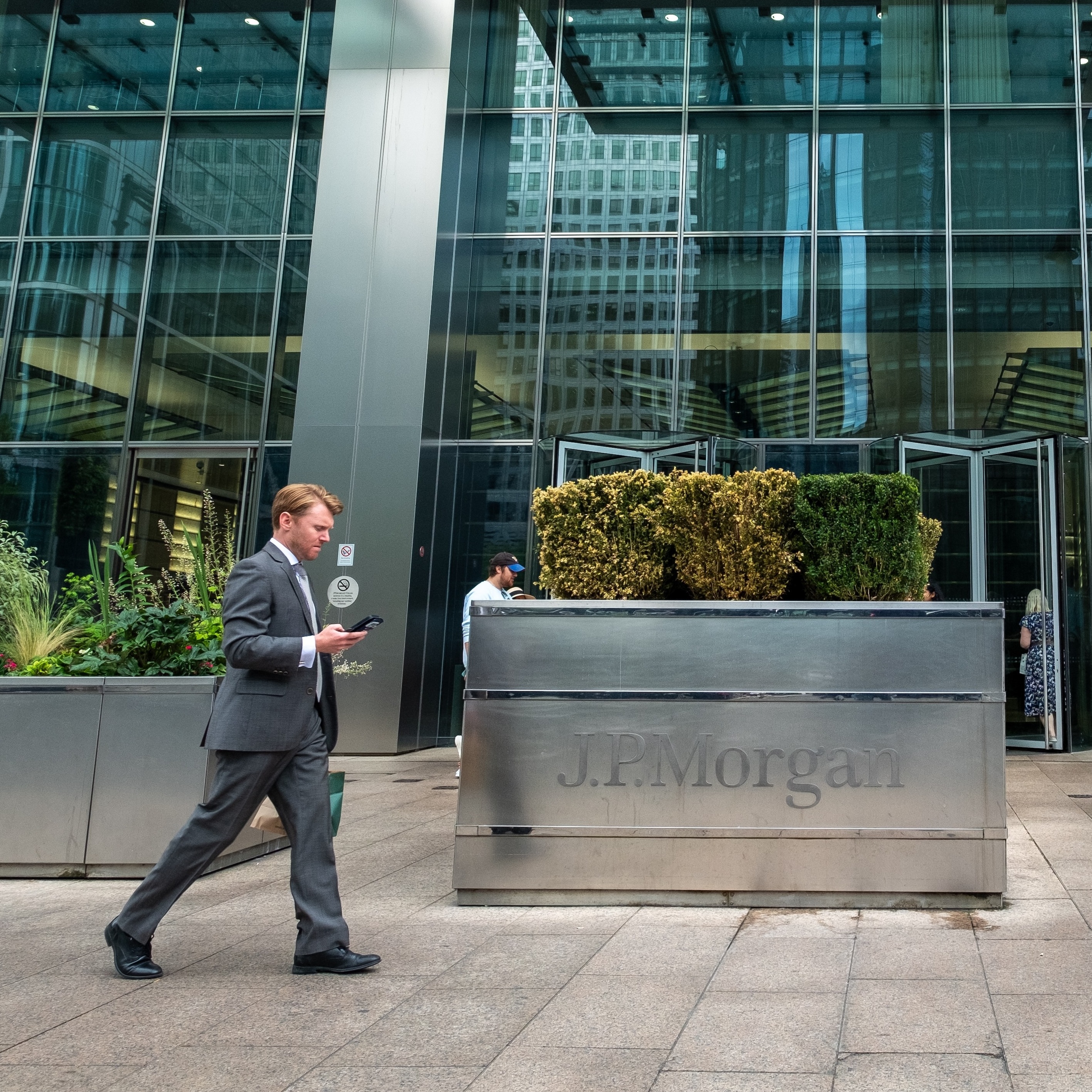 Image of a JPMorgan building with people walking in front of the signage.