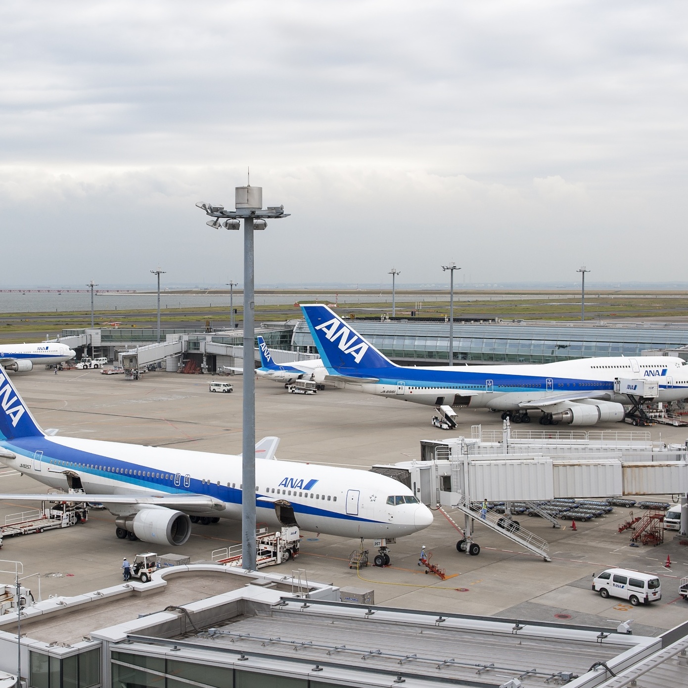 On the left a man places his luggage in bin for security, on the right Haneda airport tarmac