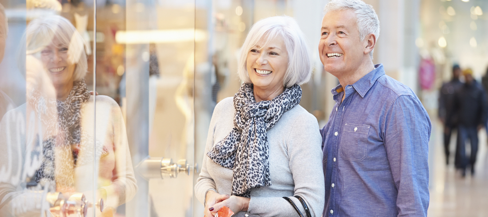 Happy Senior Couple Carrying Bags In Shopping Mall