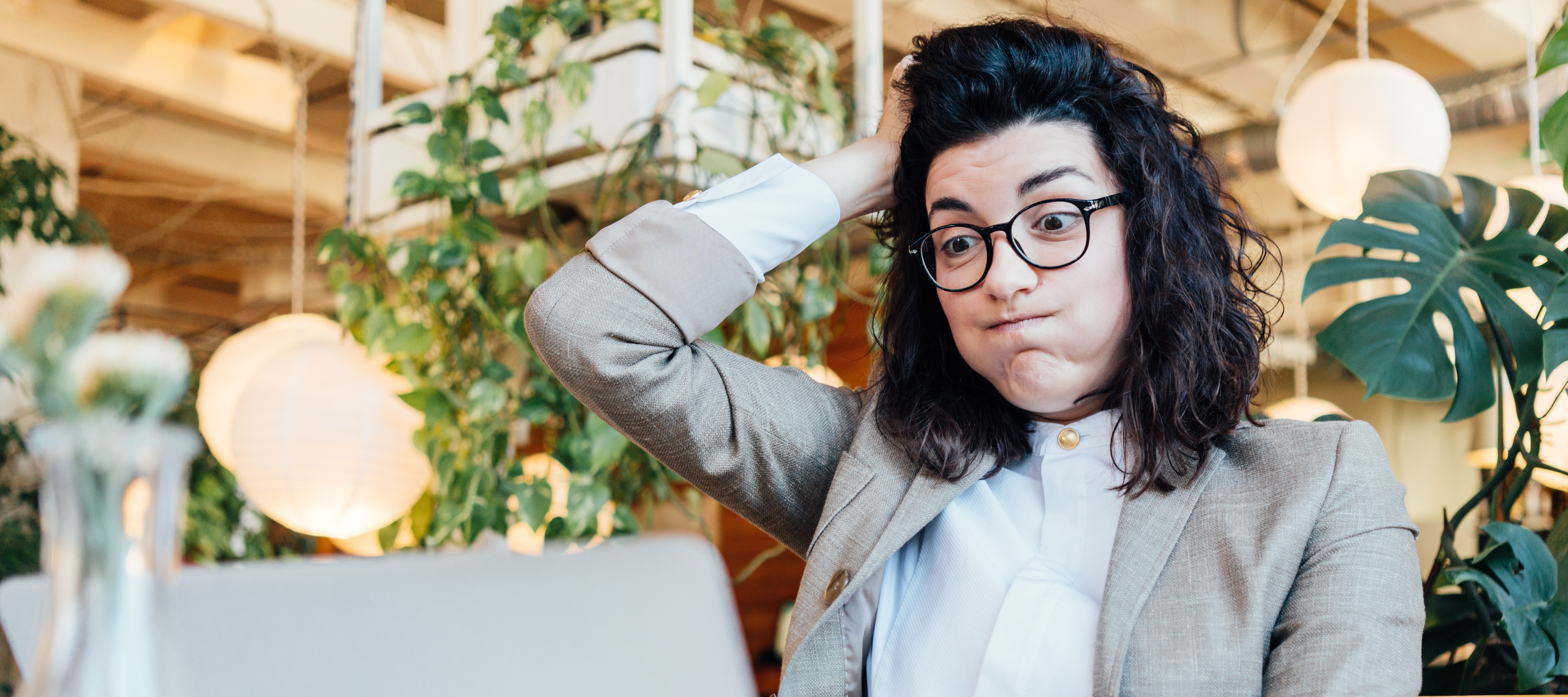 A stressed out woman puffs out her cheeks and runs a hand through her dark, curly hair.