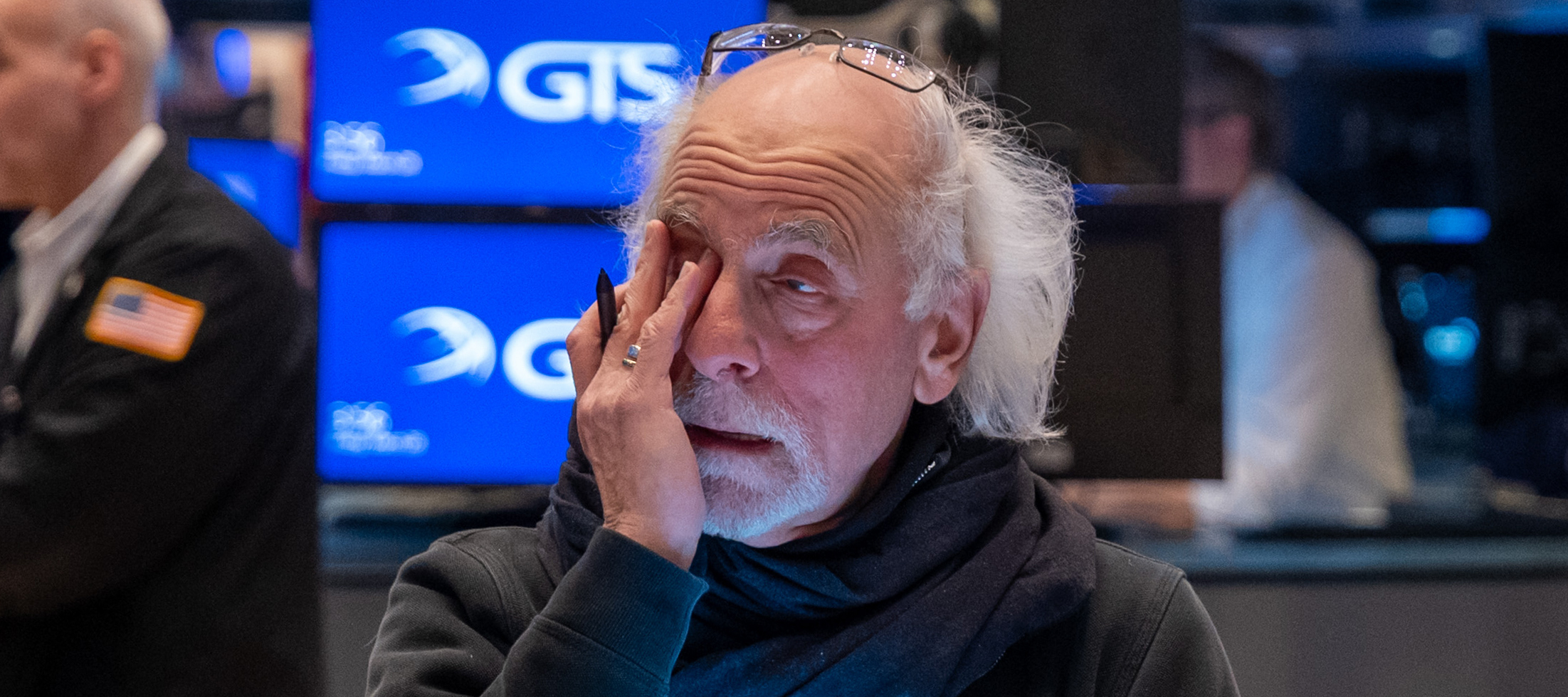 A trader on the floor of the New York Stock Exchange rubs at the corner of one eye with his hand.