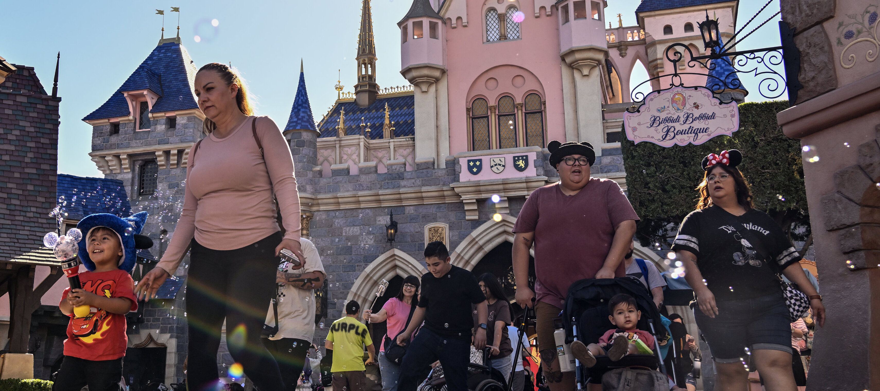 Adults and children walking through Disneyland theme park looking exhausted.