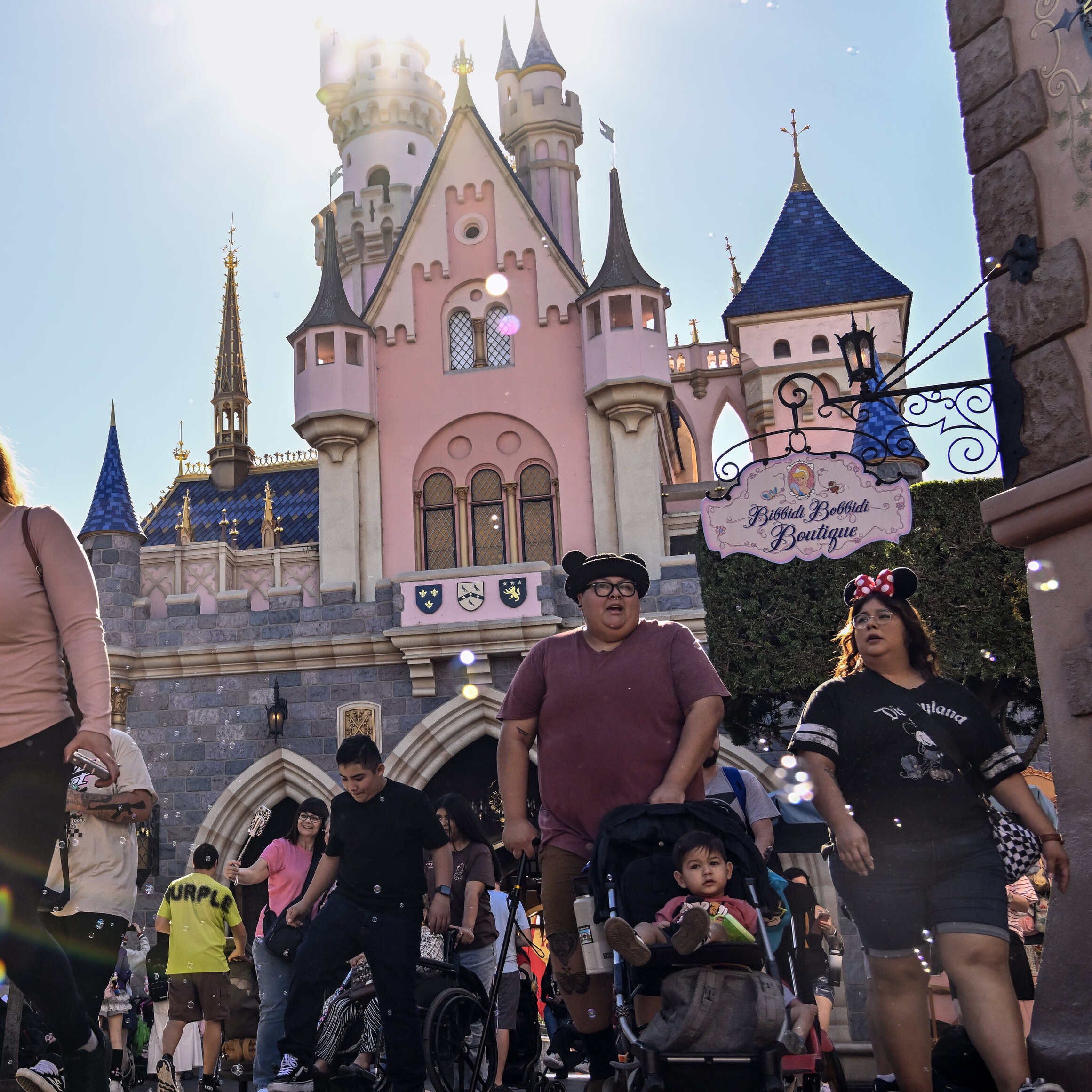 Adults and children walking through Disneyland theme park looking exhausted.