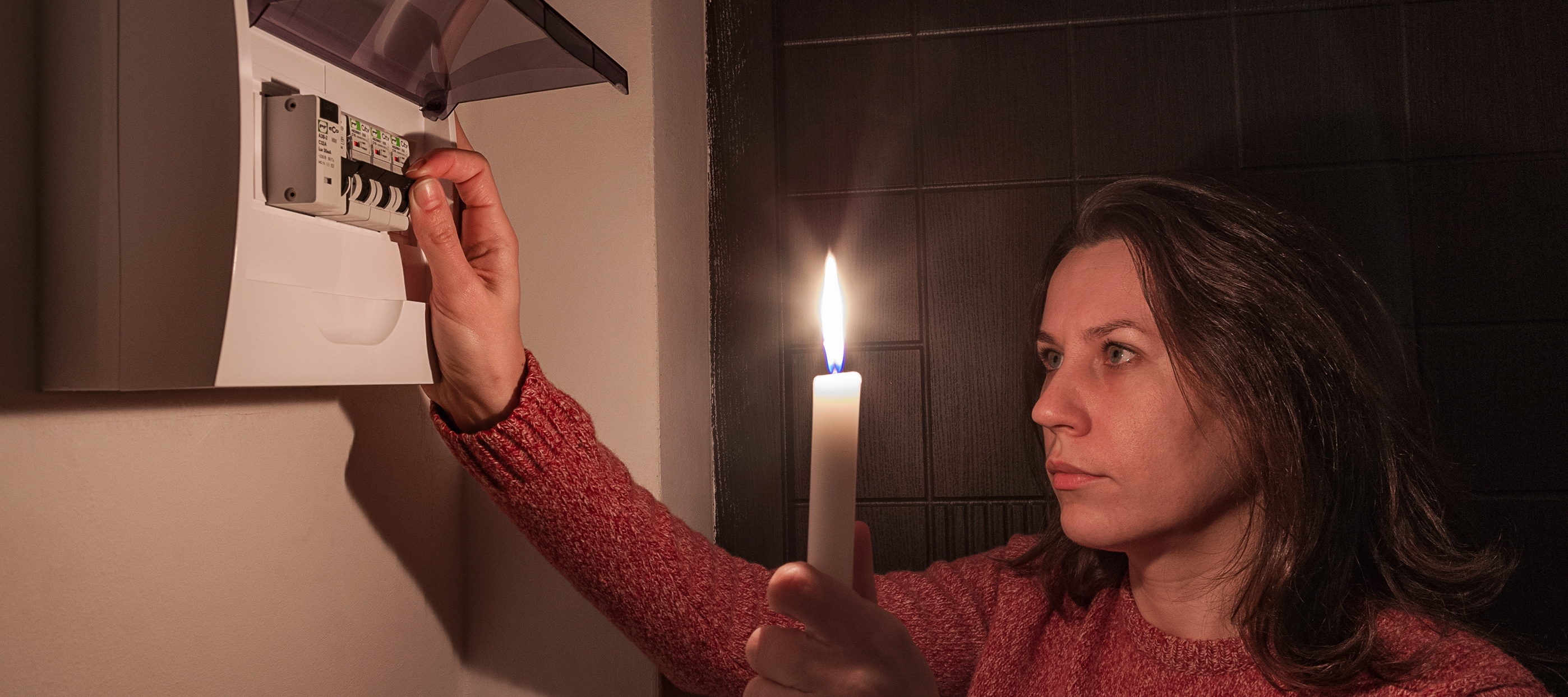 A woman turns on automatic fuses during a electric outage.