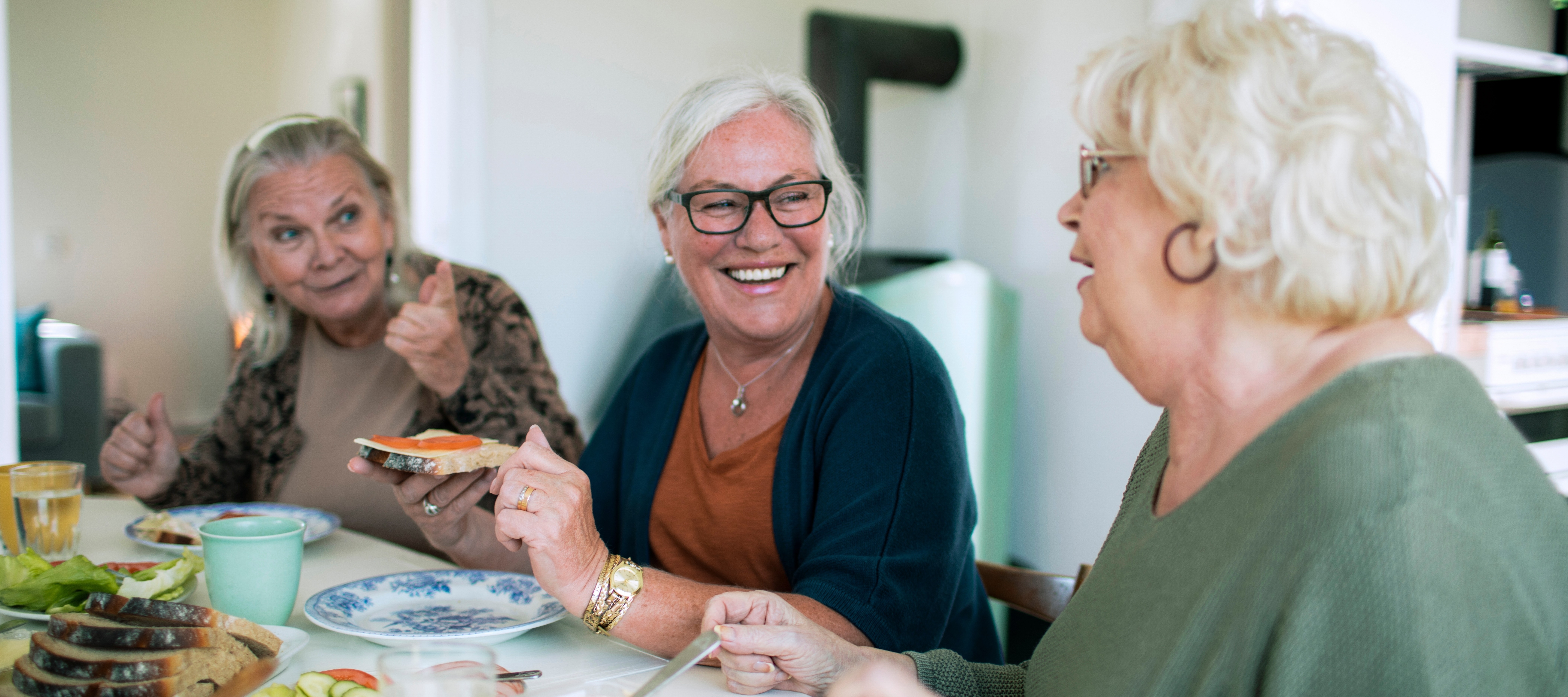 Three senior women eat breakfast together in a shared apartment. Co-living is getting more popular among older people.