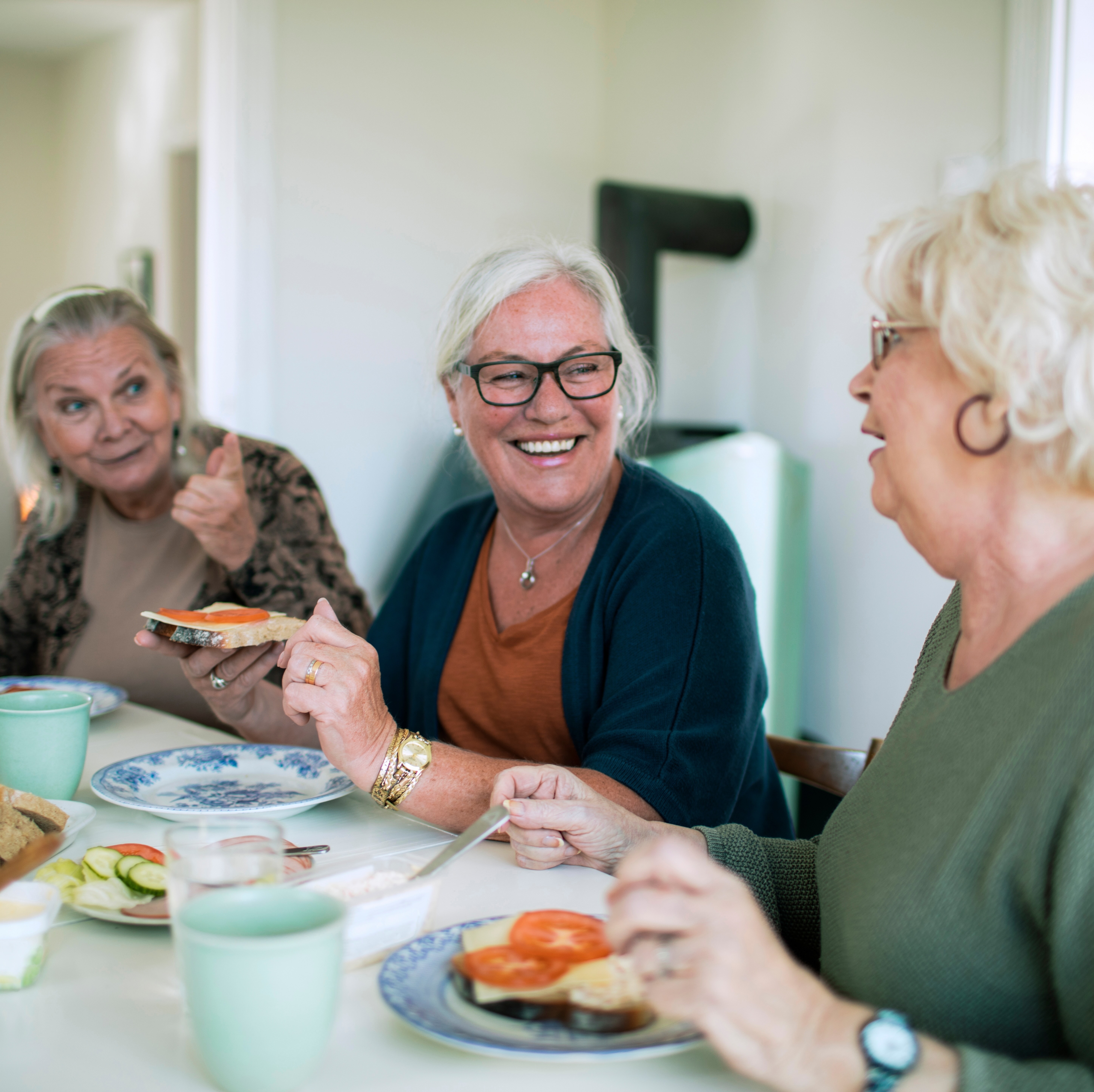 Three senior women eat breakfast together in a shared apartment. Co-living is getting more popular among older people.