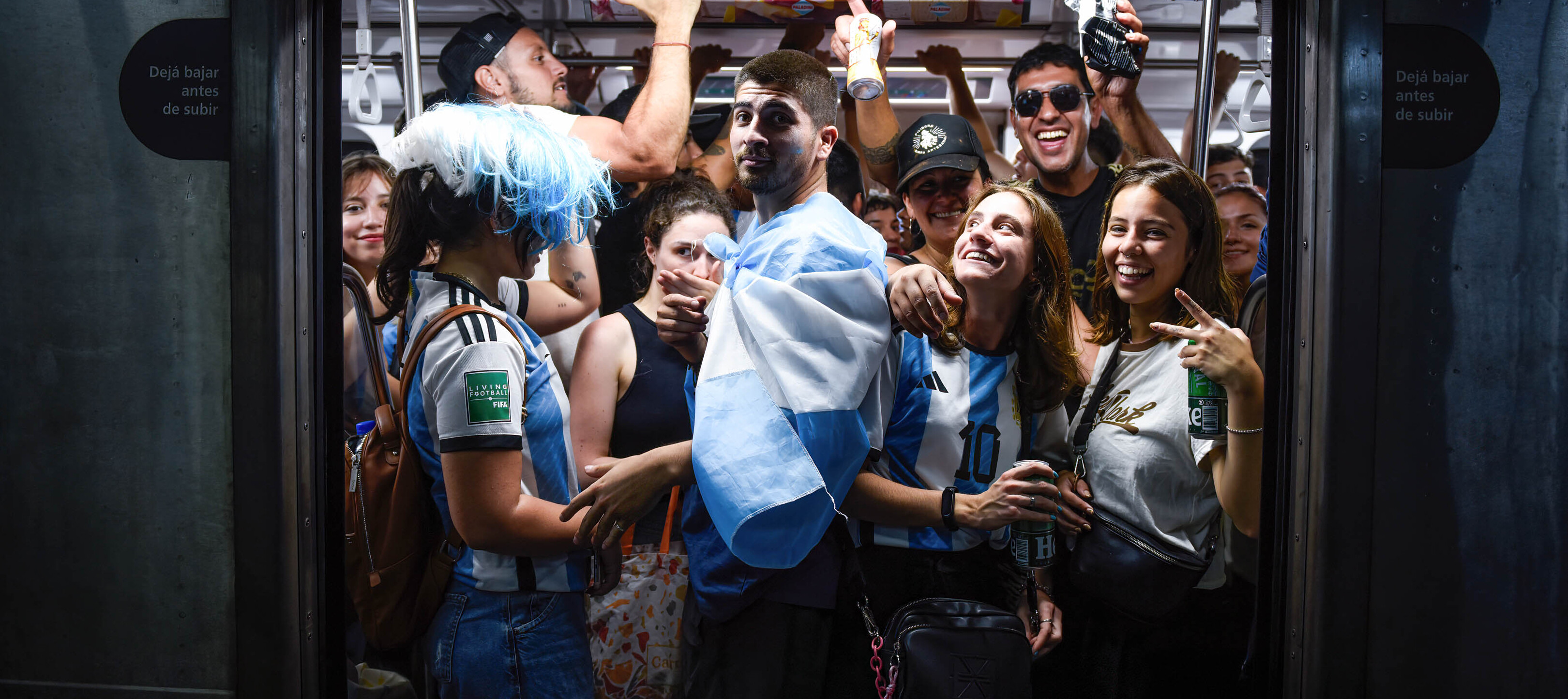 Soccer fans celebrate the World Cup while inside a packed subway car.