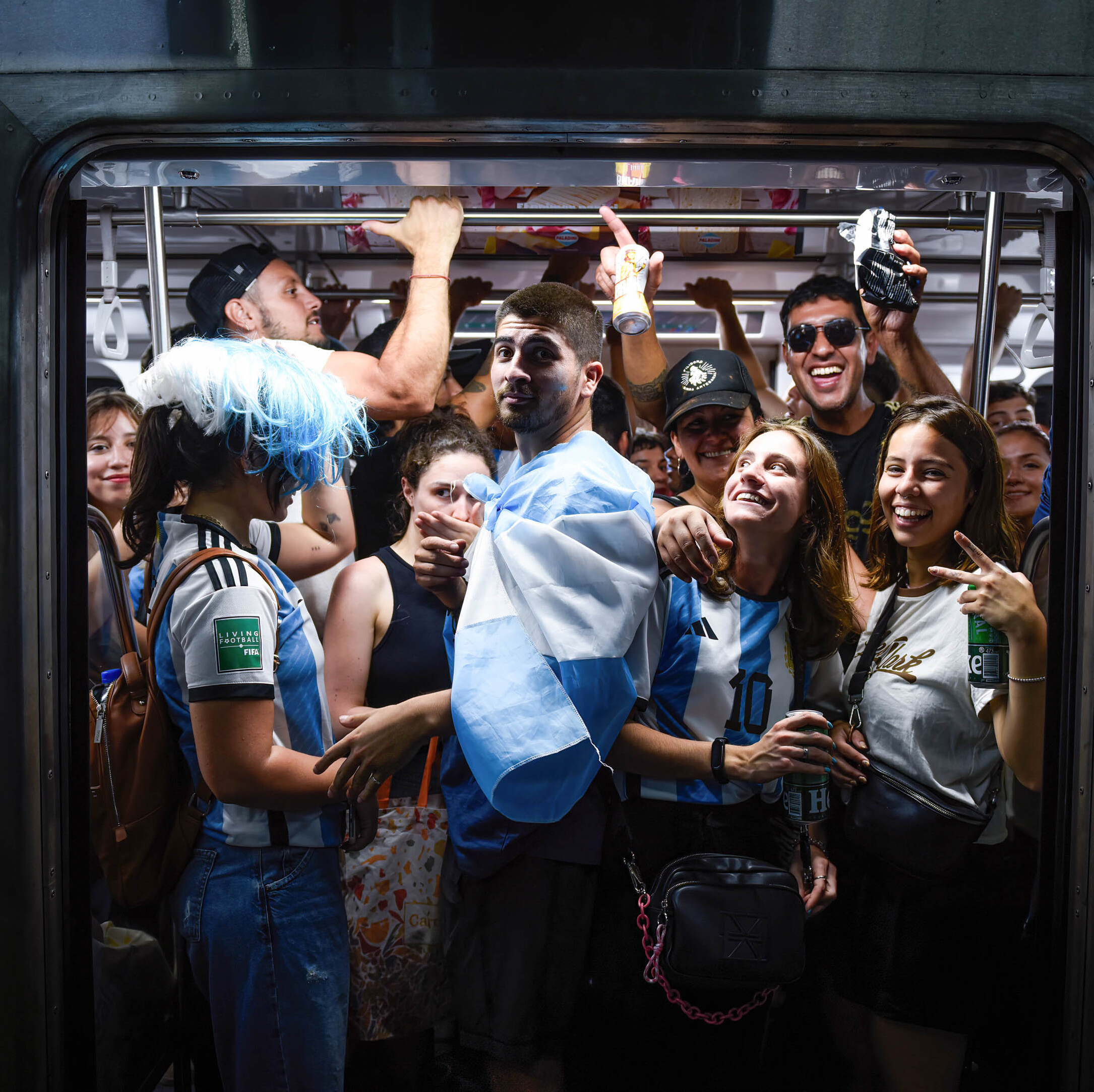 Soccer fans celebrate the World Cup while inside a packed subway car.