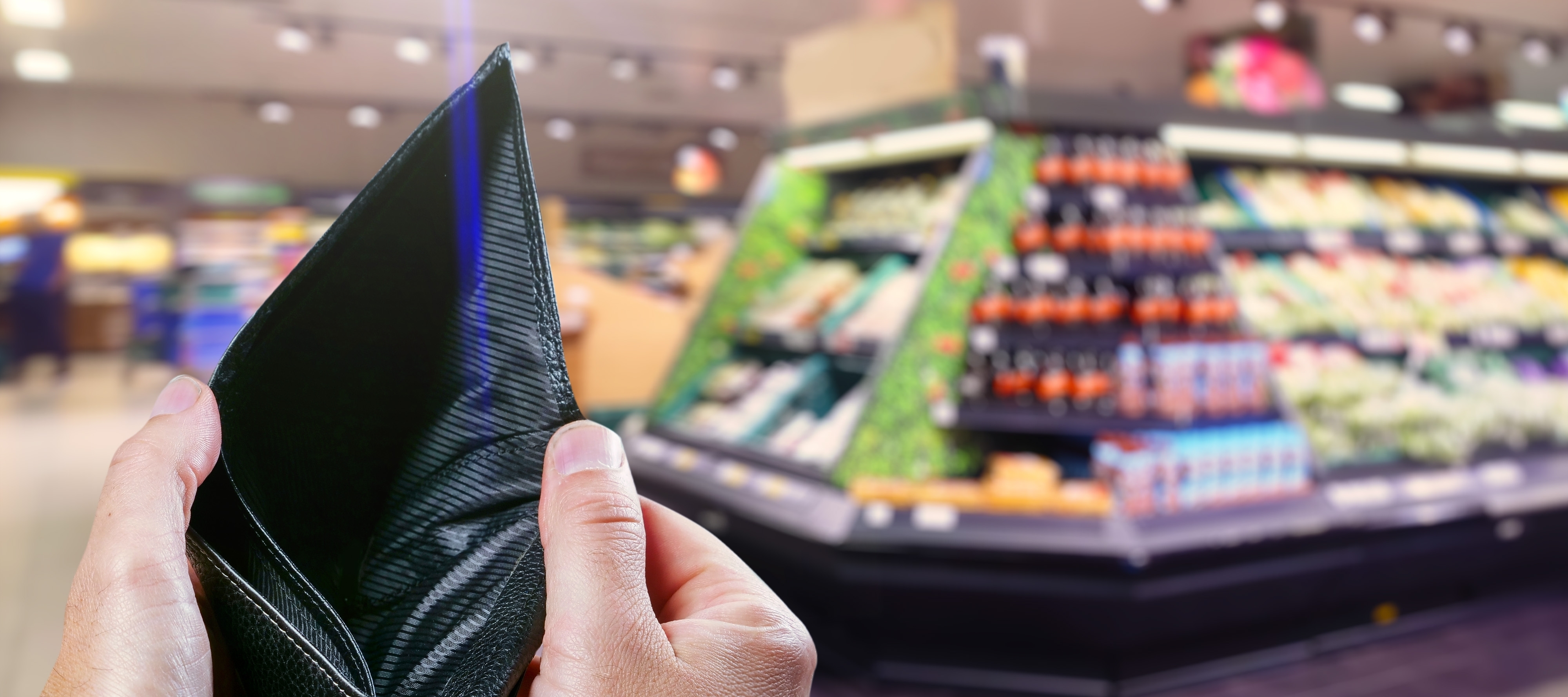 Grocery shopper with an empty wallet in hand, taking in rising food prices.
