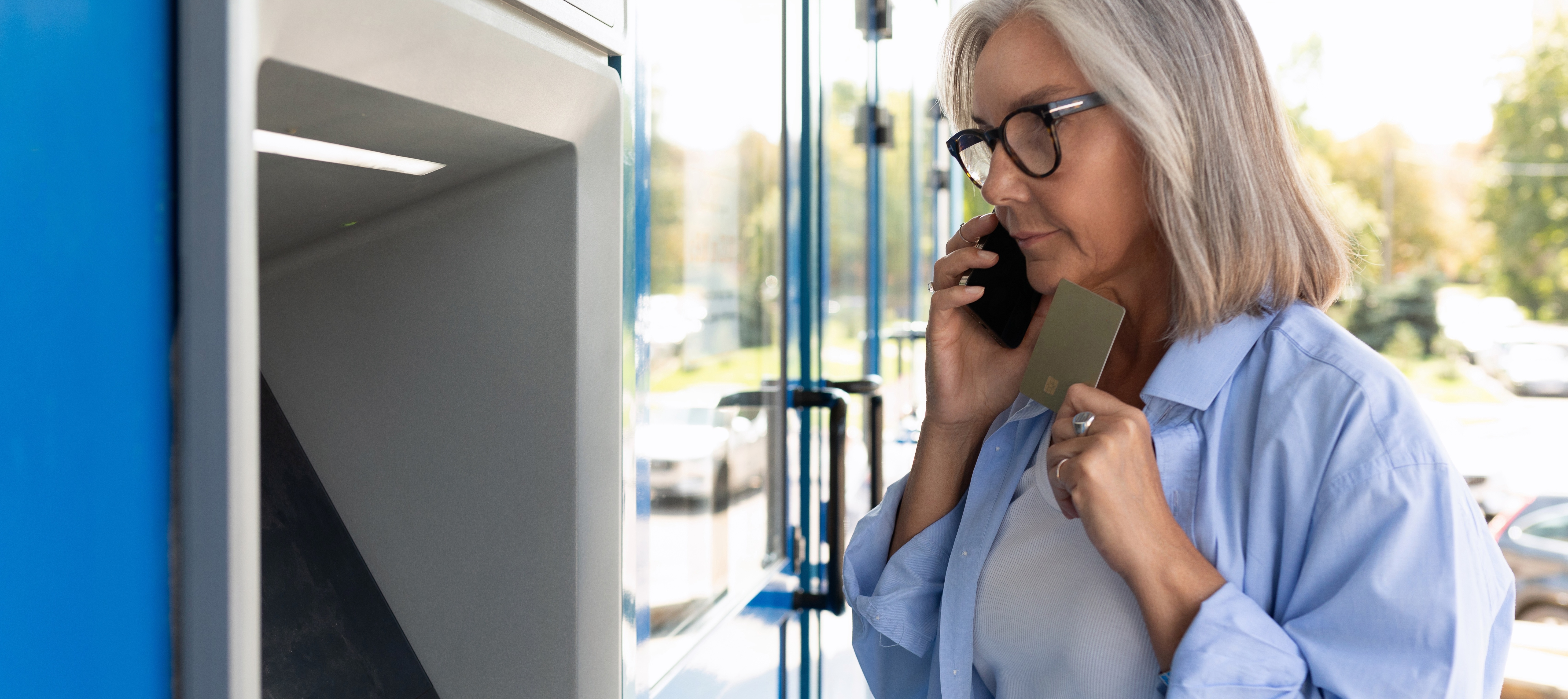 A woman seen talking on the phone in front of an ATM as online romance scammers continue to fool victims, with $298 million in losses reported in 2025.