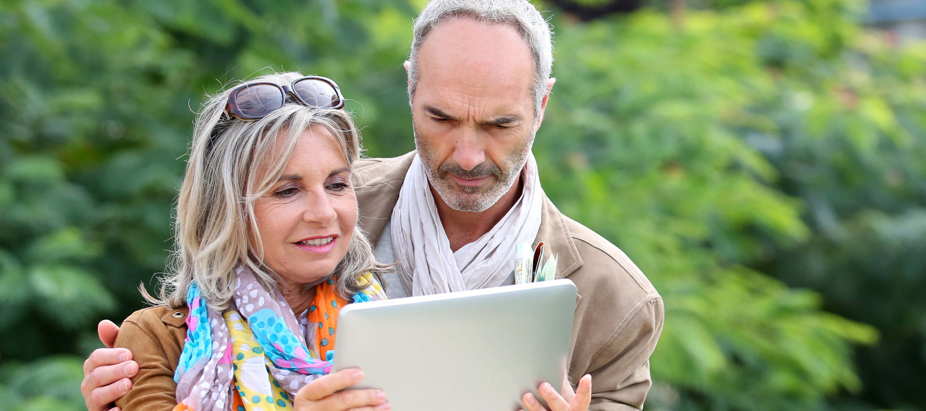 Mature couple looking at a tablet while outside