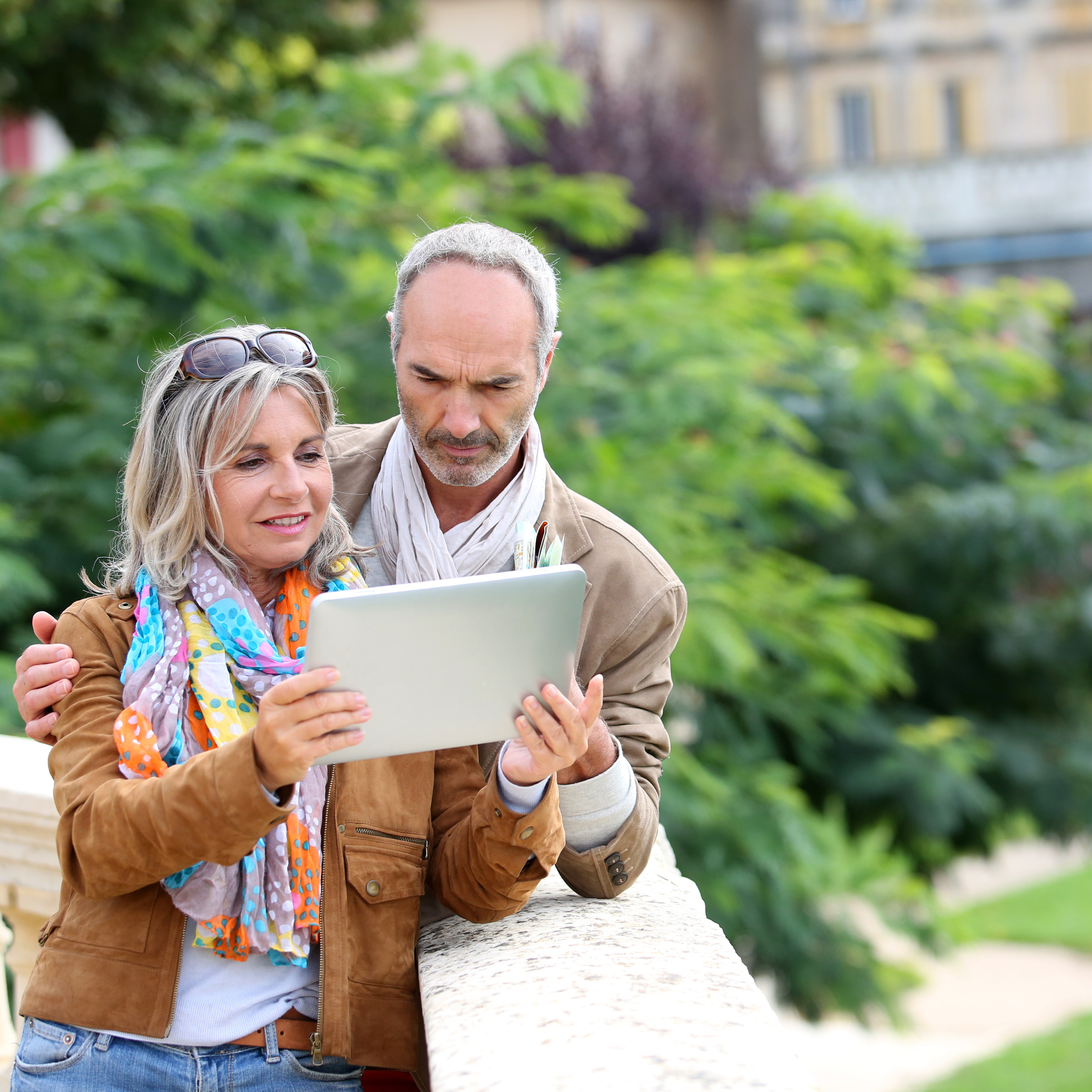 Mature couple looking at a tablet while outside
