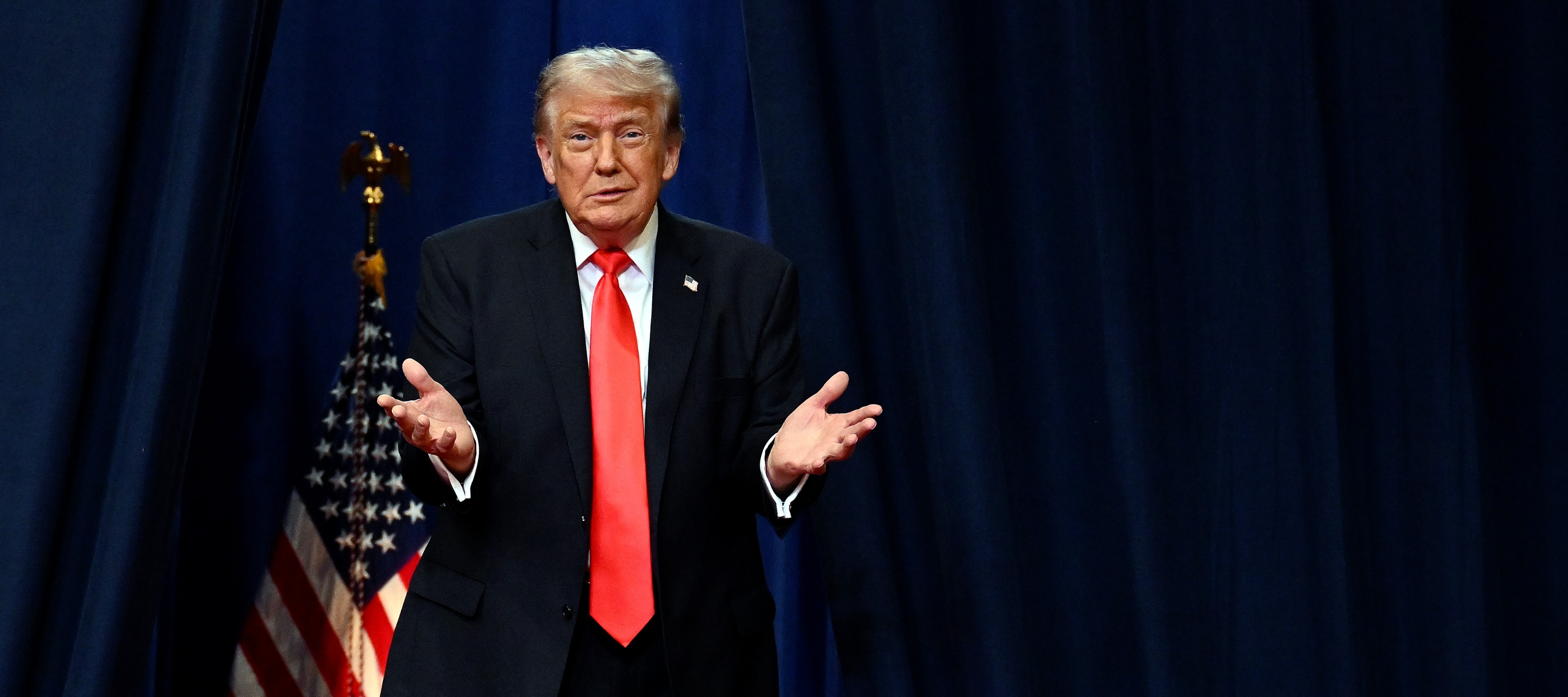 Donald Trump shrugging in front of an American flag
