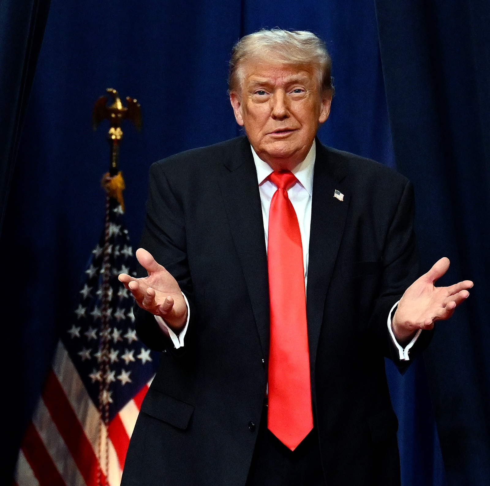 Donald Trump shrugging in front of an American flag