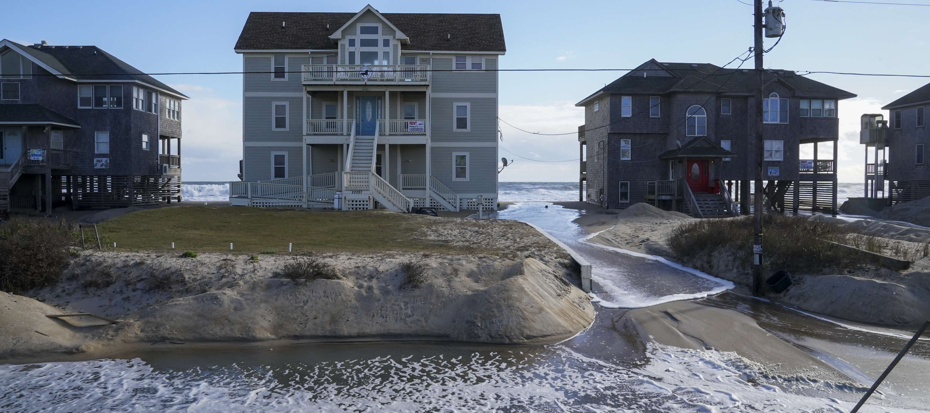 Ocean waves wash past houses to flood Seagull Street on the Outer Banks of North Carolina.