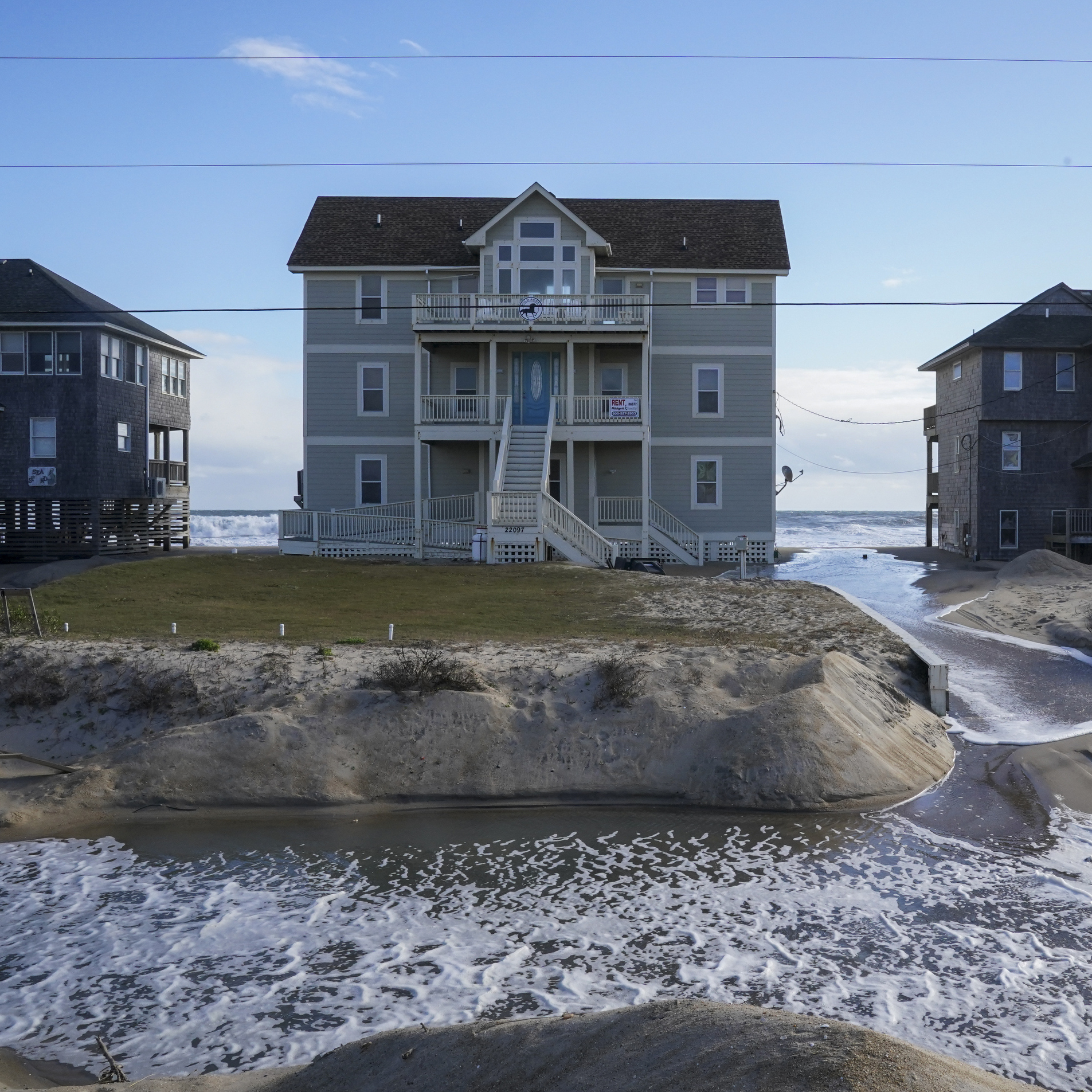 Ocean waves wash past houses to flood Seagull Street on the Outer Banks of North Carolina.