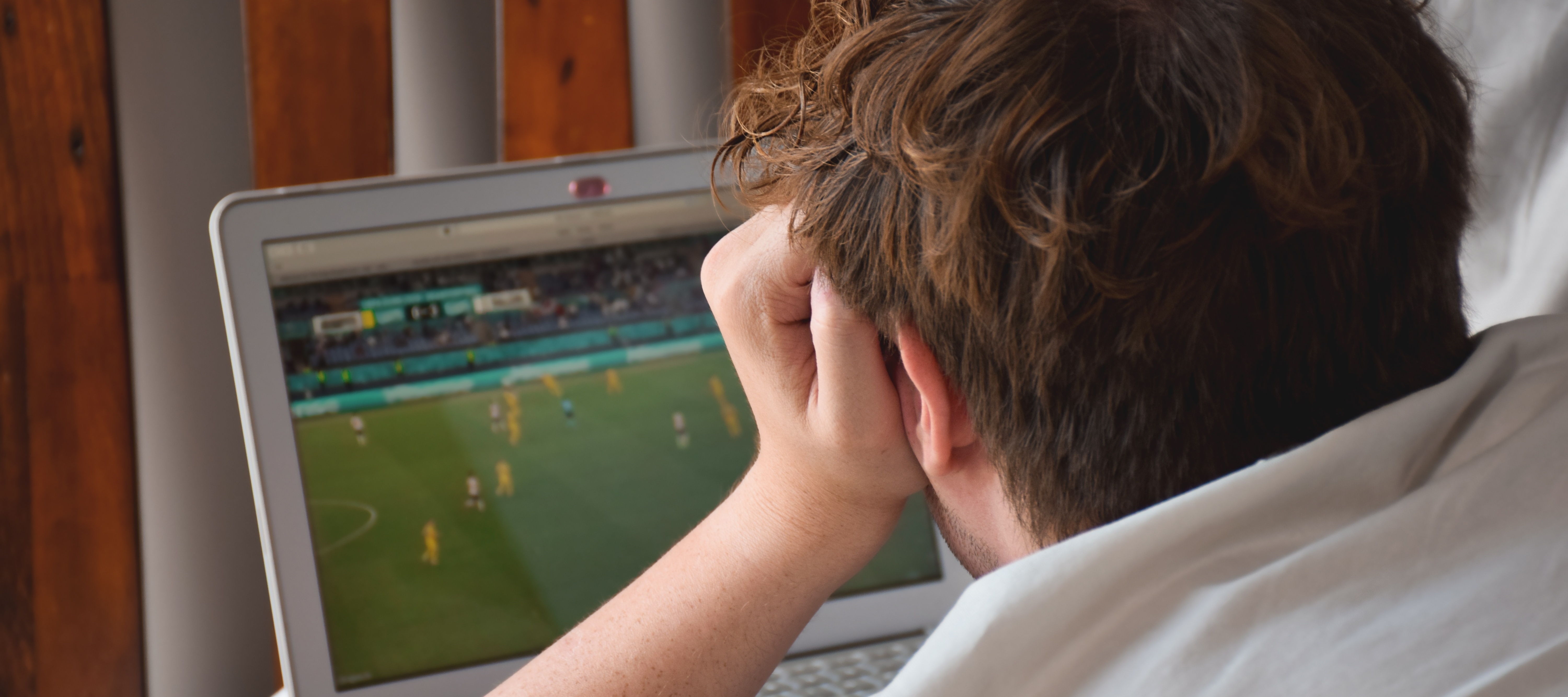 Gen Z man watching soccer on laptop
