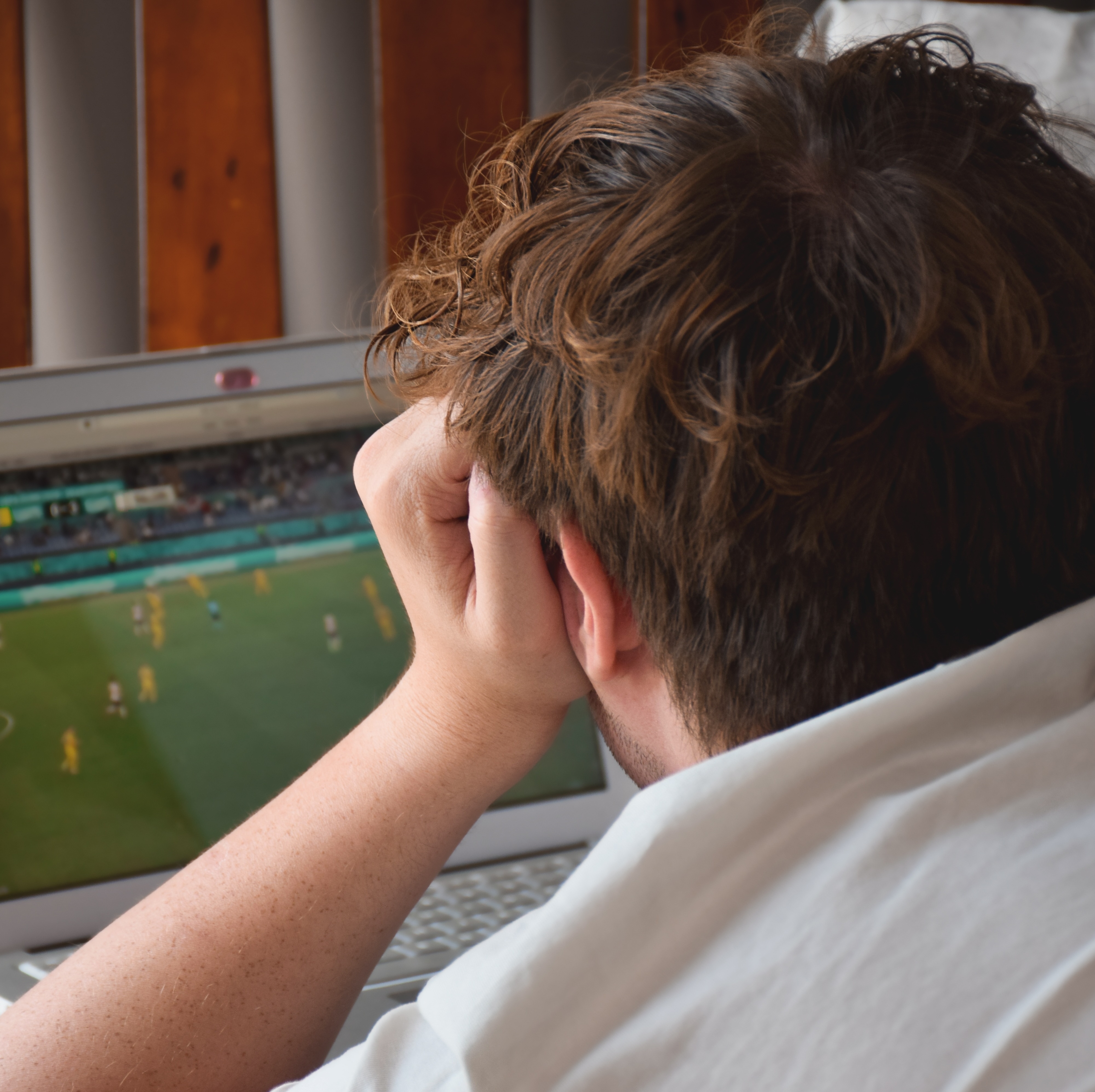 Gen Z man watching soccer on laptop